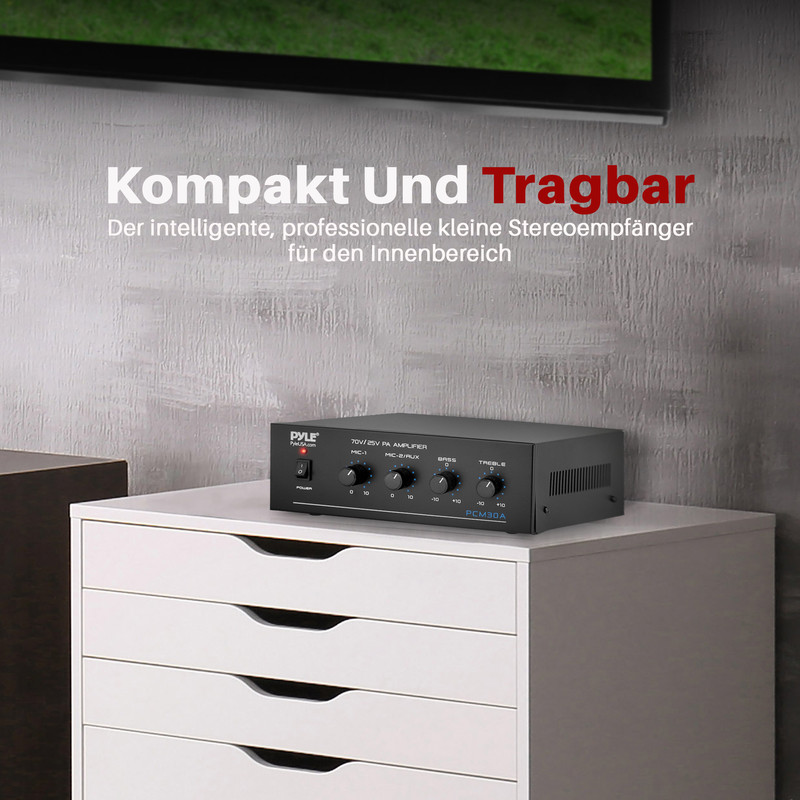 Schwarzer Verstärker auf weißem Schrank vor grauer Wand.