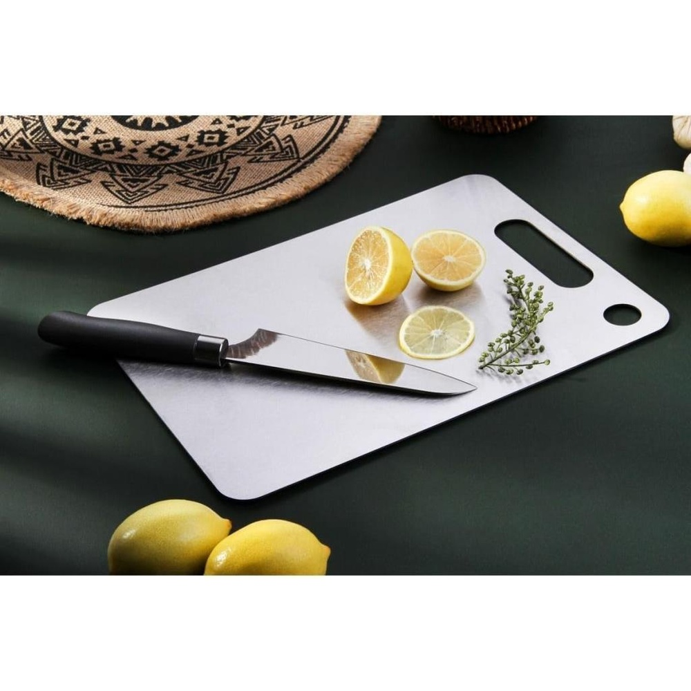 Bir bıçak, limon dilimleri ve dallarla metal bir kesme tahtasının üzerinde duruyor.