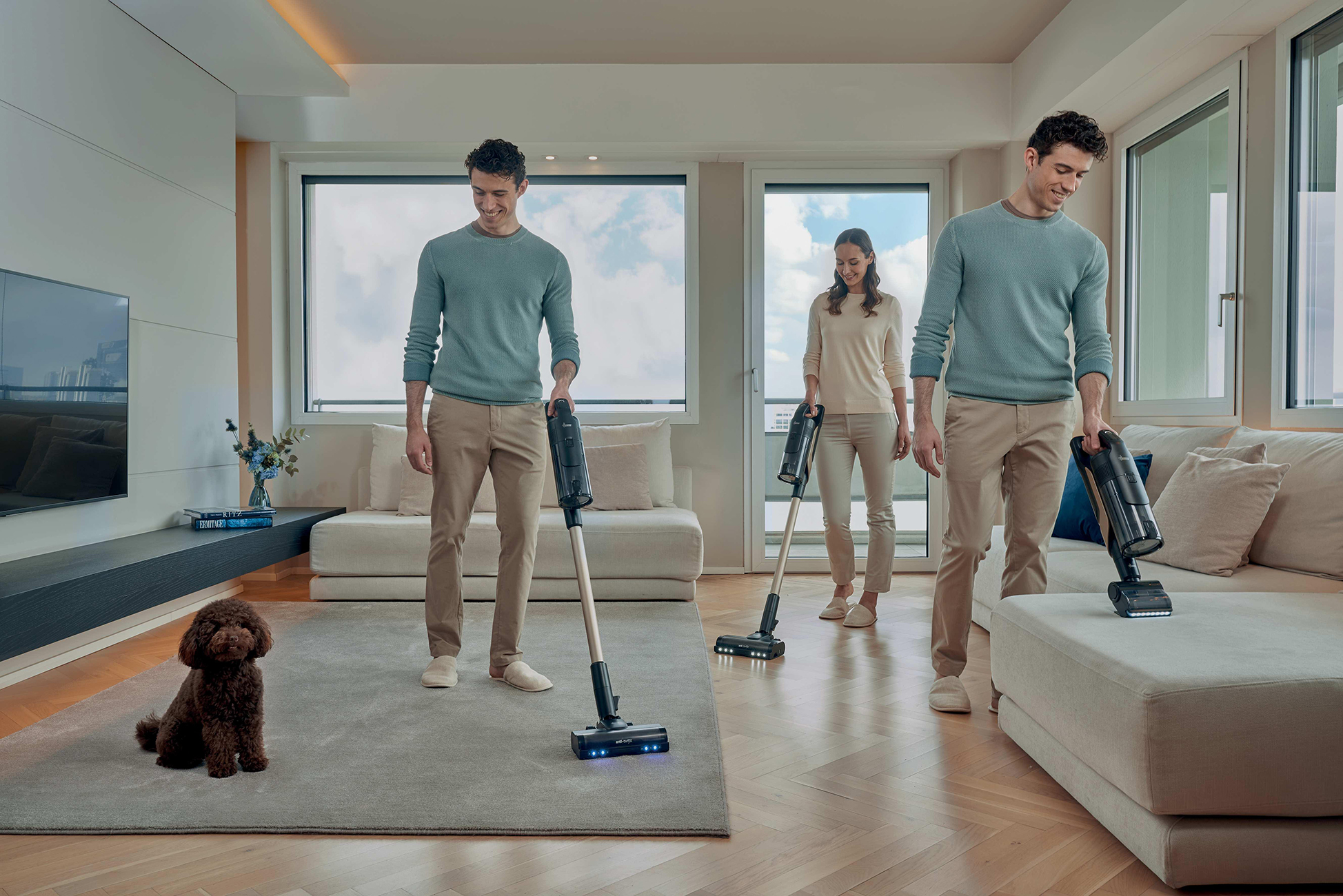 Un uomo e una donna aspirano un soggiorno, un cane è seduto su un tappeto.