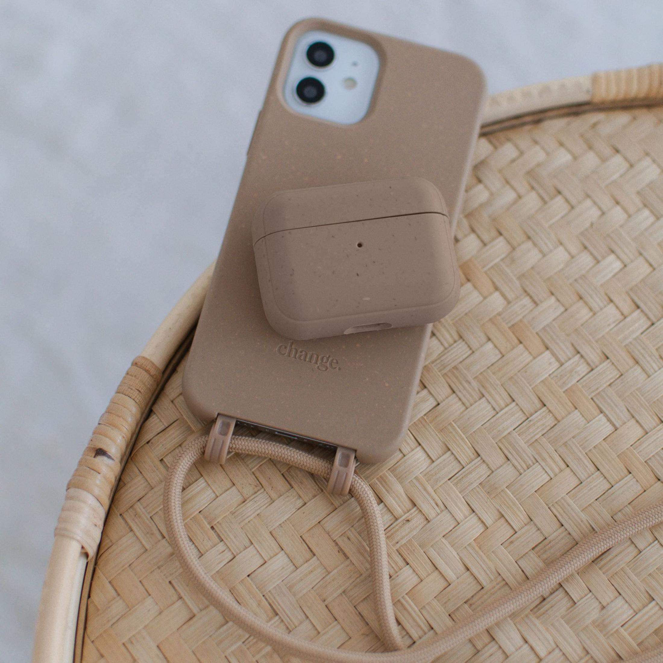 Ein beige iPhone und Hülle liegen auf einem Korbtisch.
