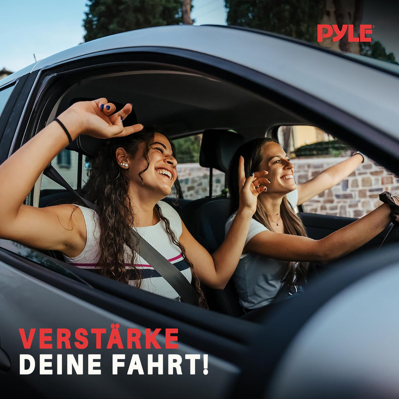 Zwei junge Frauen fahren lachend im Auto, eine winkt aus dem Fenster.