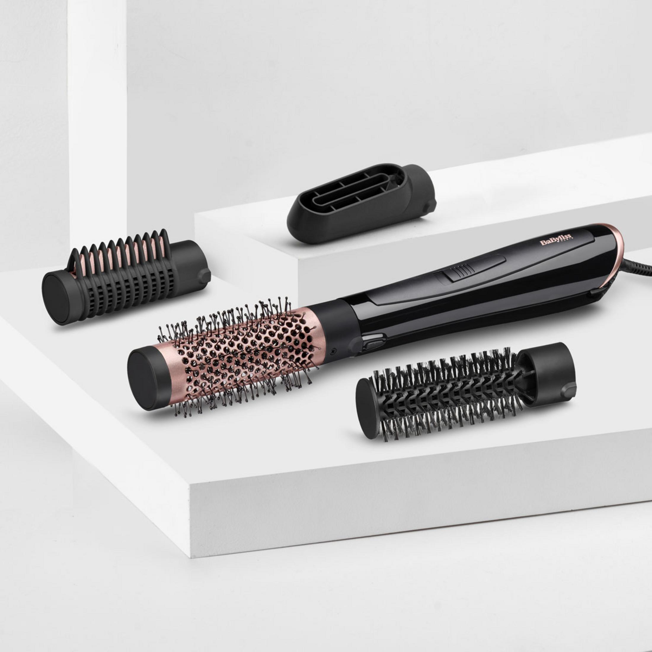 Un asciugacapelli Babyliss nero con tre accessori su piedistalli bianchi.