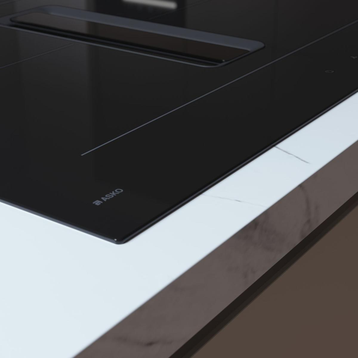 Primo piano di un piano cottura a induzione nero con cappa aspirante integrata e piano di lavoro in marmo.