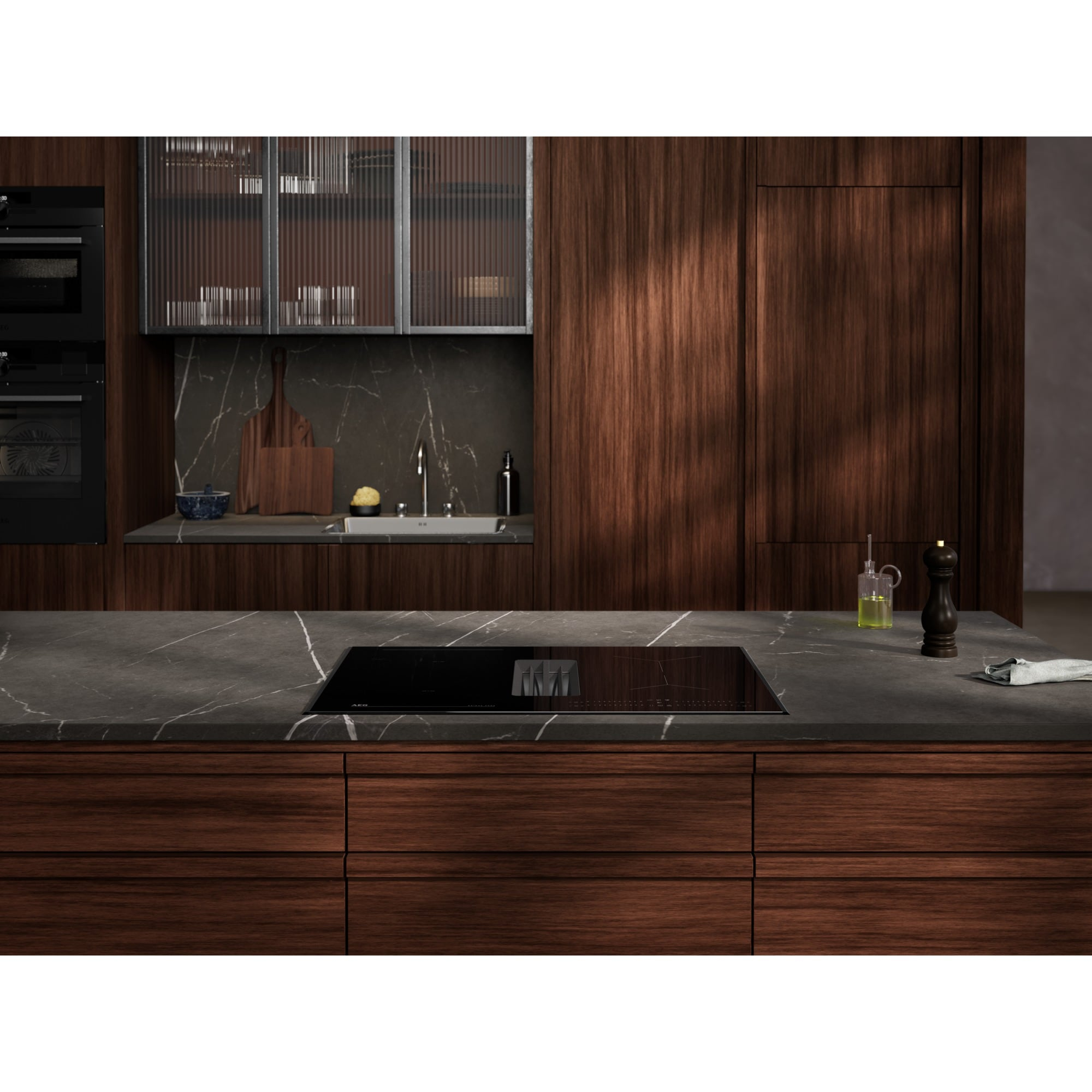 Cucina moderna con mobili in legno scuro e piano di lavoro in marmo. Piano cottura a induzione.