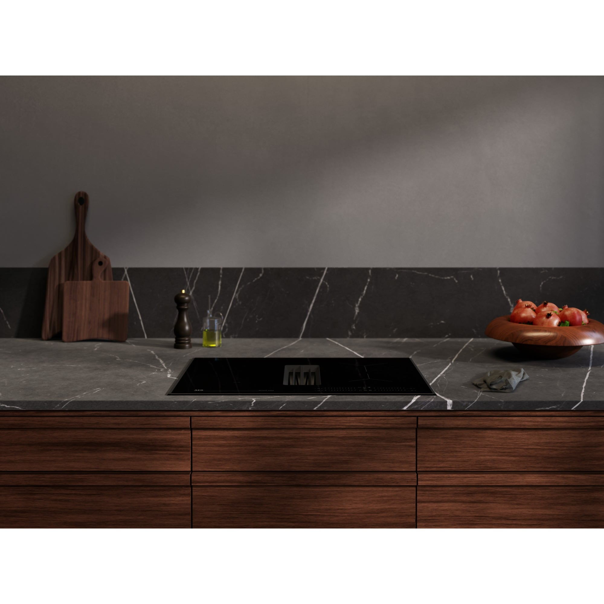 Cucina moderna con piano di lavoro in marmo nero, piano cottura e cassetti in legno.