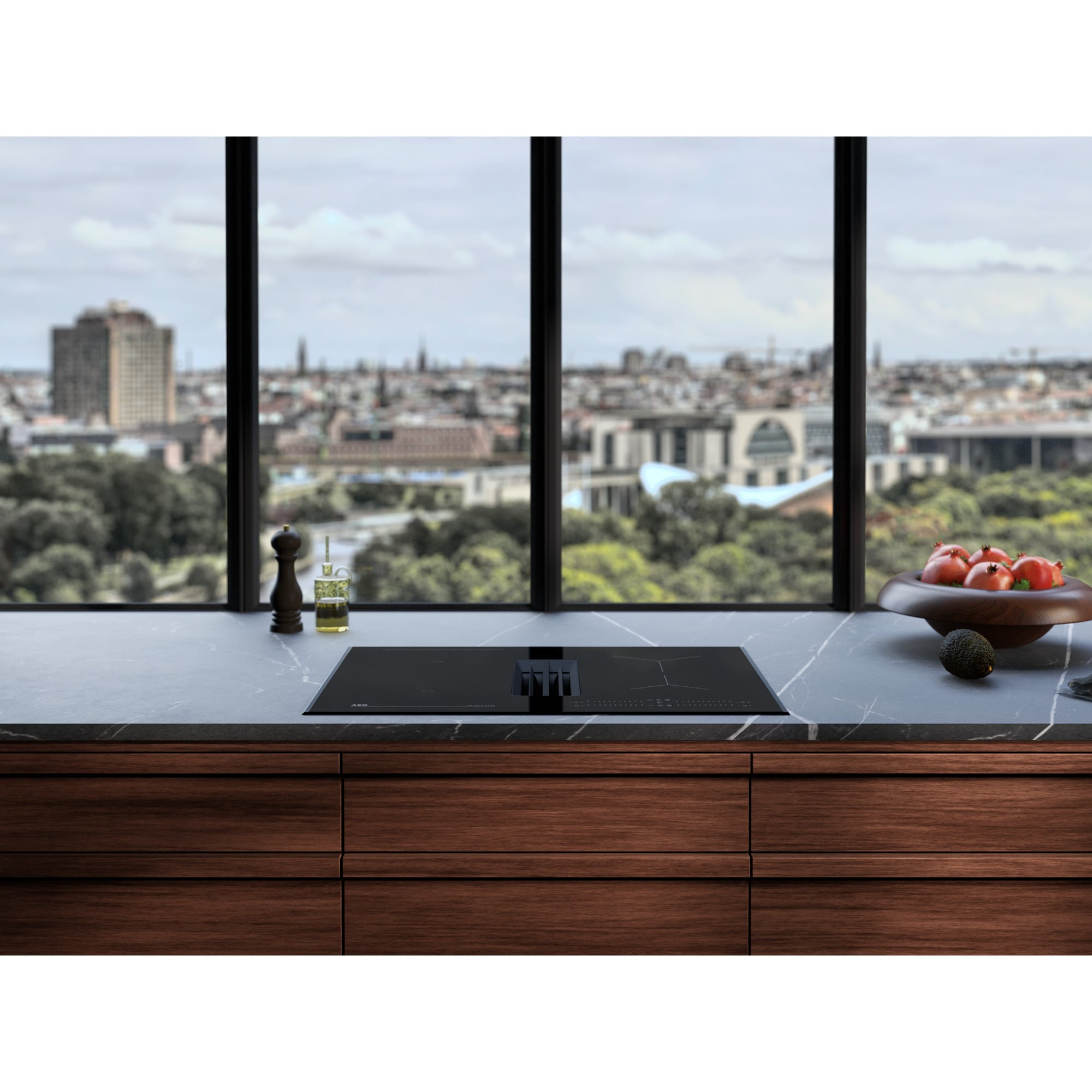 Cucina moderna con piano cottura a induzione, ciotola di frutta e vista città.