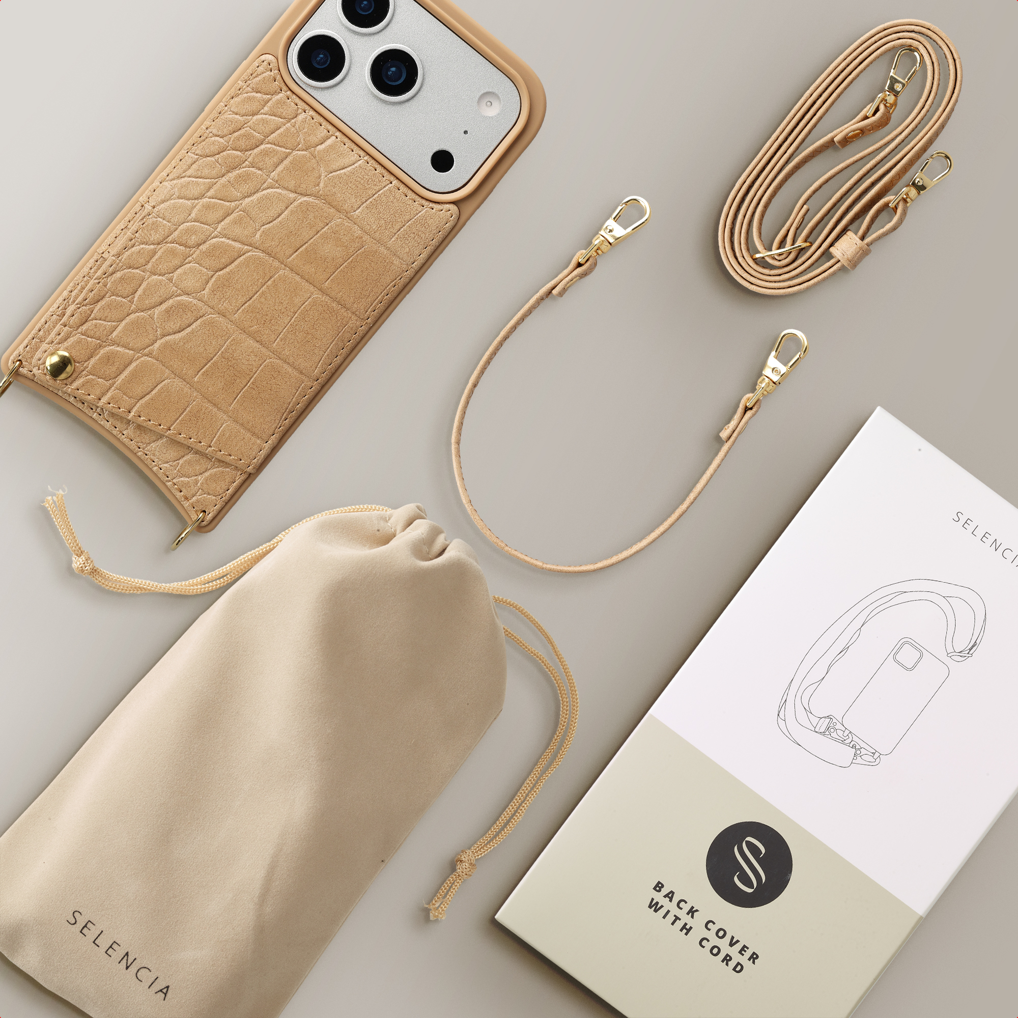 Una funda de teléfono marrón claro con relieve de cocodrilo, un bolso y un cordón.
