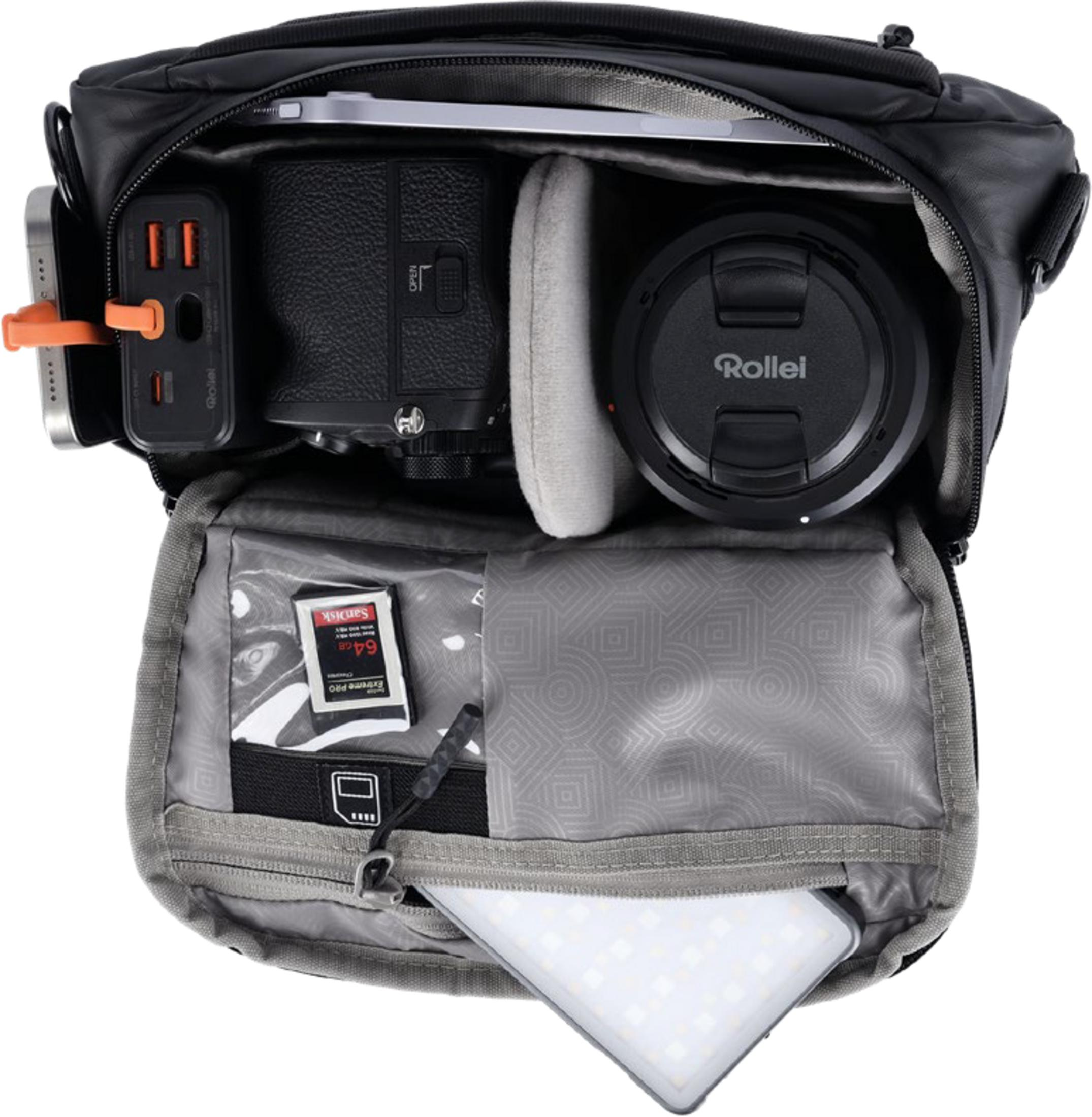 Eine schwarze Kameratasche mit Ausrüstung: Kamera, Objektiv, Powerbank, SD-Karte, Handy, Licht.