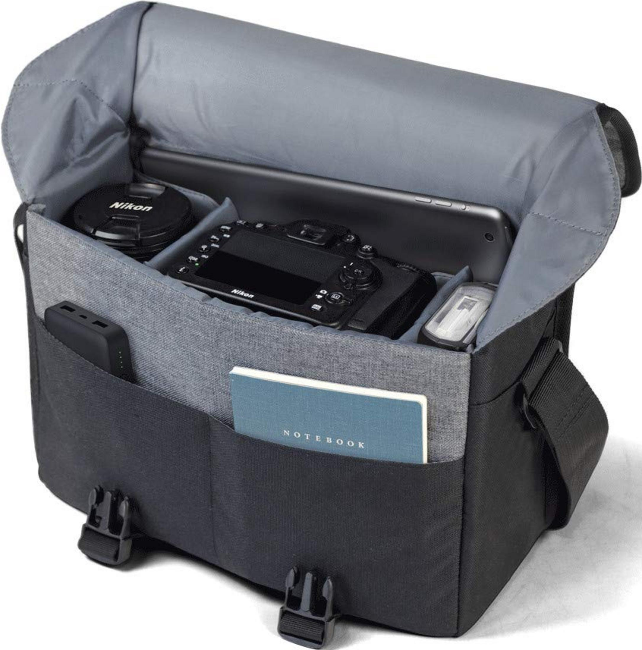 Eine offene graue Kameratasche mit Kamera, Tablet, Powerbank und Notizbuch.