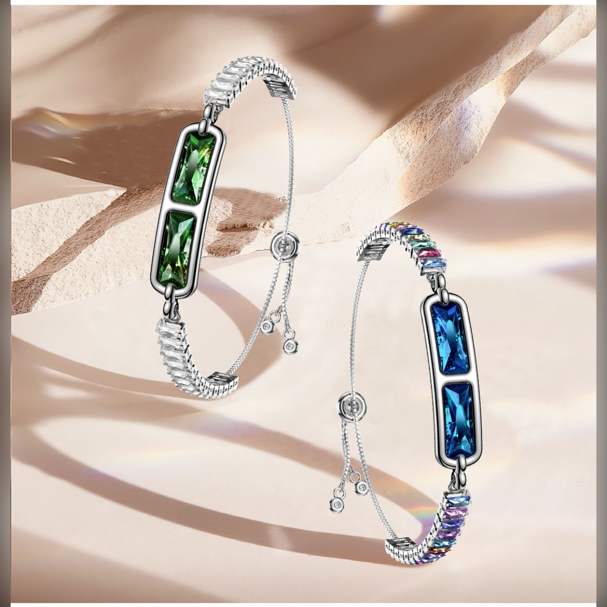 Zwei silberne Armbänder mit bunten und grünen Edelsteinen auf hellem Hintergrund.