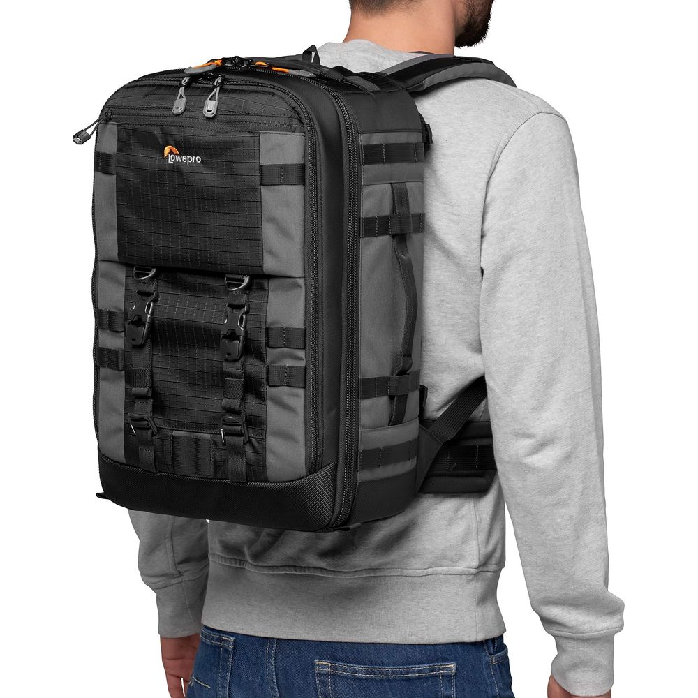 Eine Person trägt einen großen schwarzen und grauen Rucksack mit mehreren Riemen und Taschen.