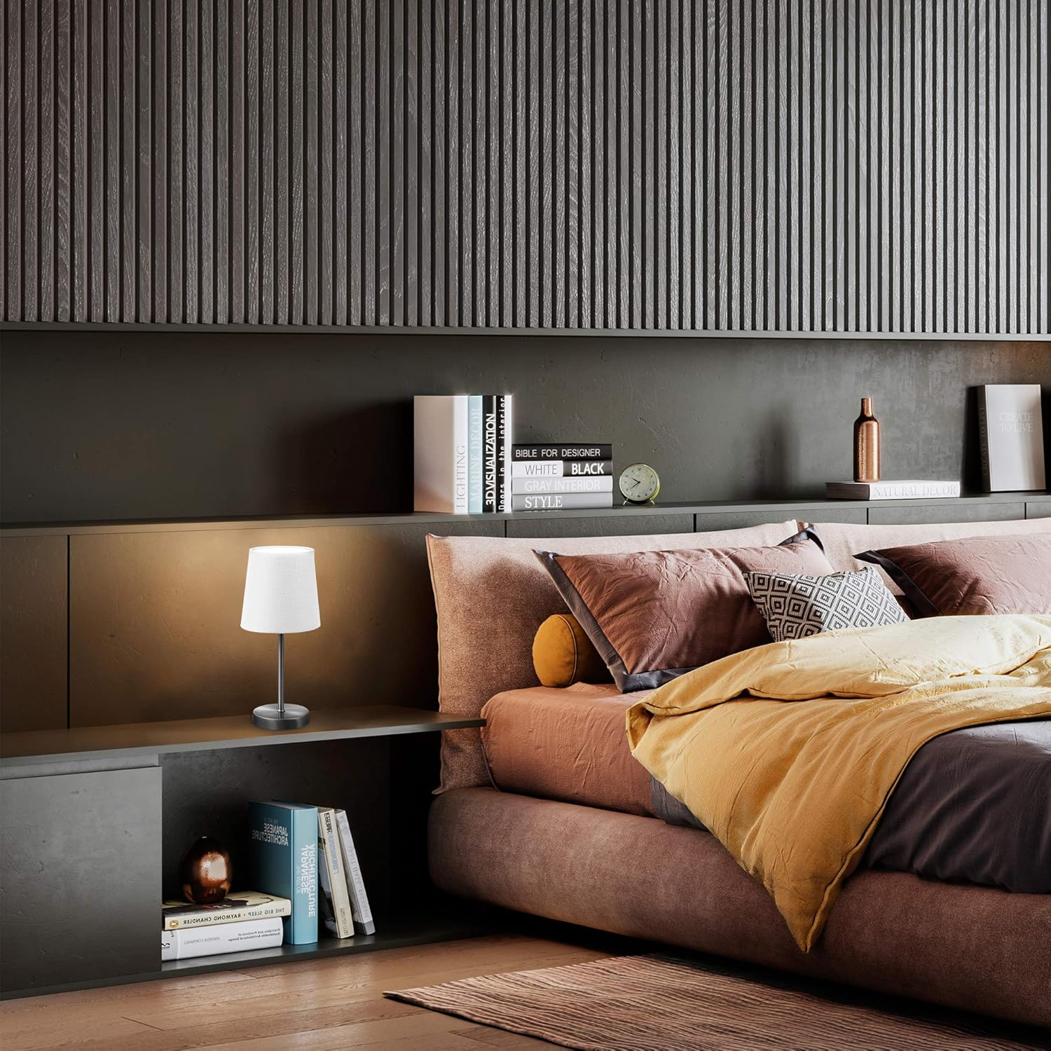 Ein Nachttisch mit Lampe und Büchern vor einem Bett mit gelber Decke.