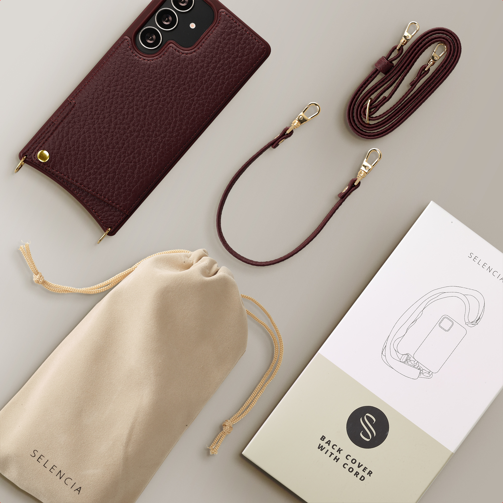 Maroon leather phone case with strap, pouch, and packaging.