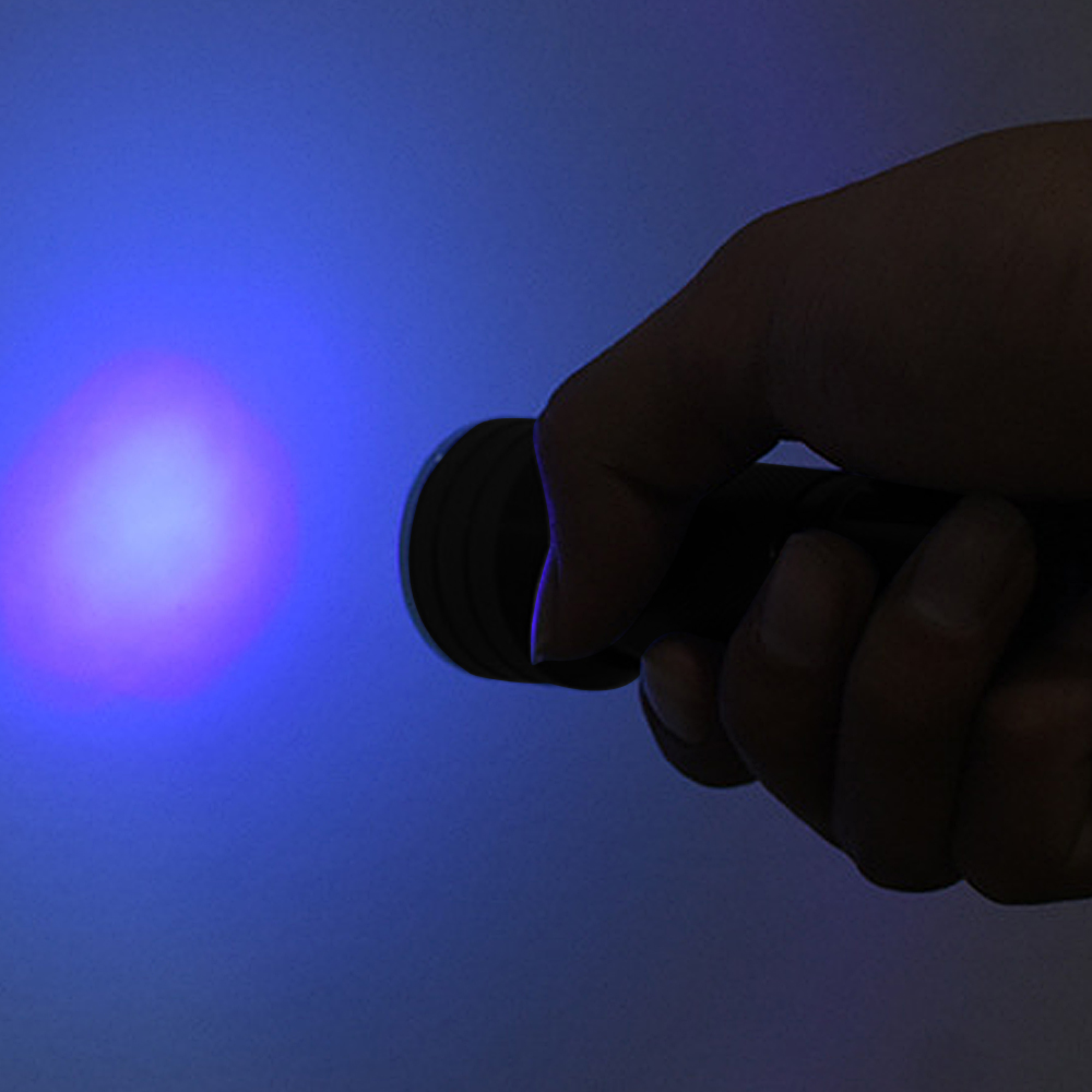 Eine Hand hält einen dunklen Gegenstand, der ein helles blaues Licht ausstrahlt.