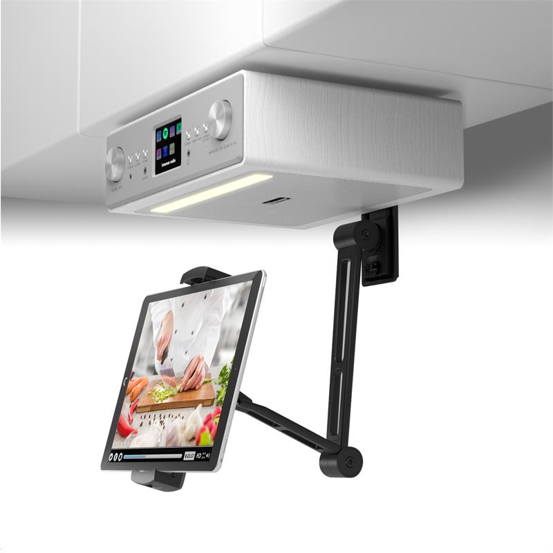 Ein Koch schneidet auf einem Brett Gemüse. Ein Küchenradio hängt über einem Tablet.