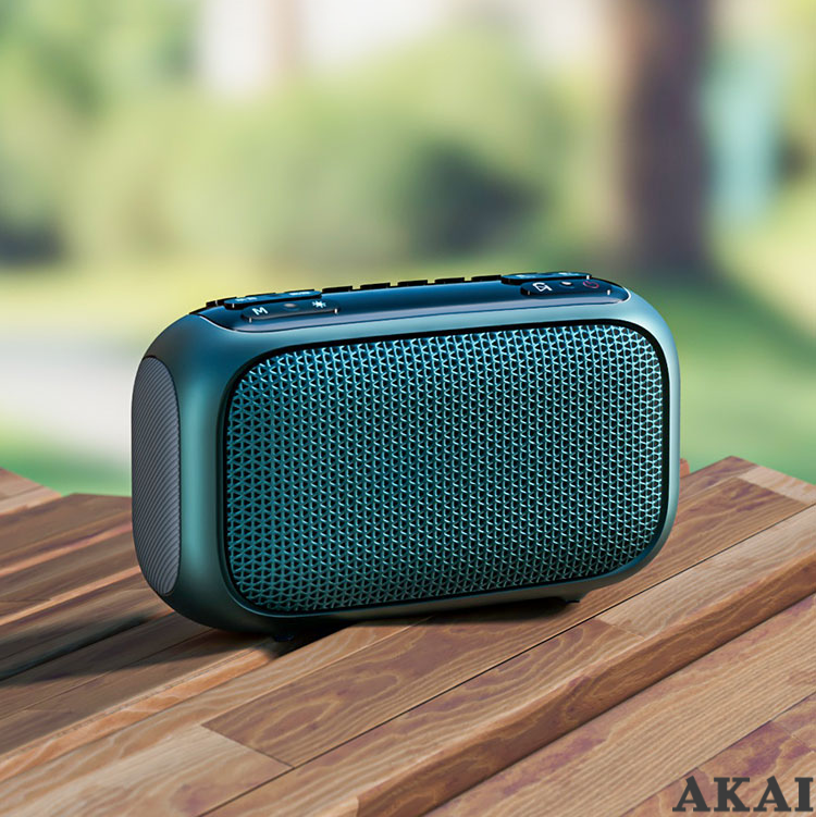 Un altoparlante Bluetooth blu poggia su una superficie di legno con vegetazione sfocata.