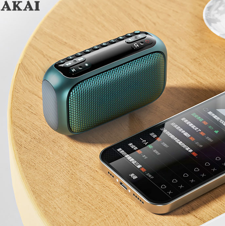 Un altoparlante AKAI verde e uno smartphone con elenco musicale su un tavolo di legno.