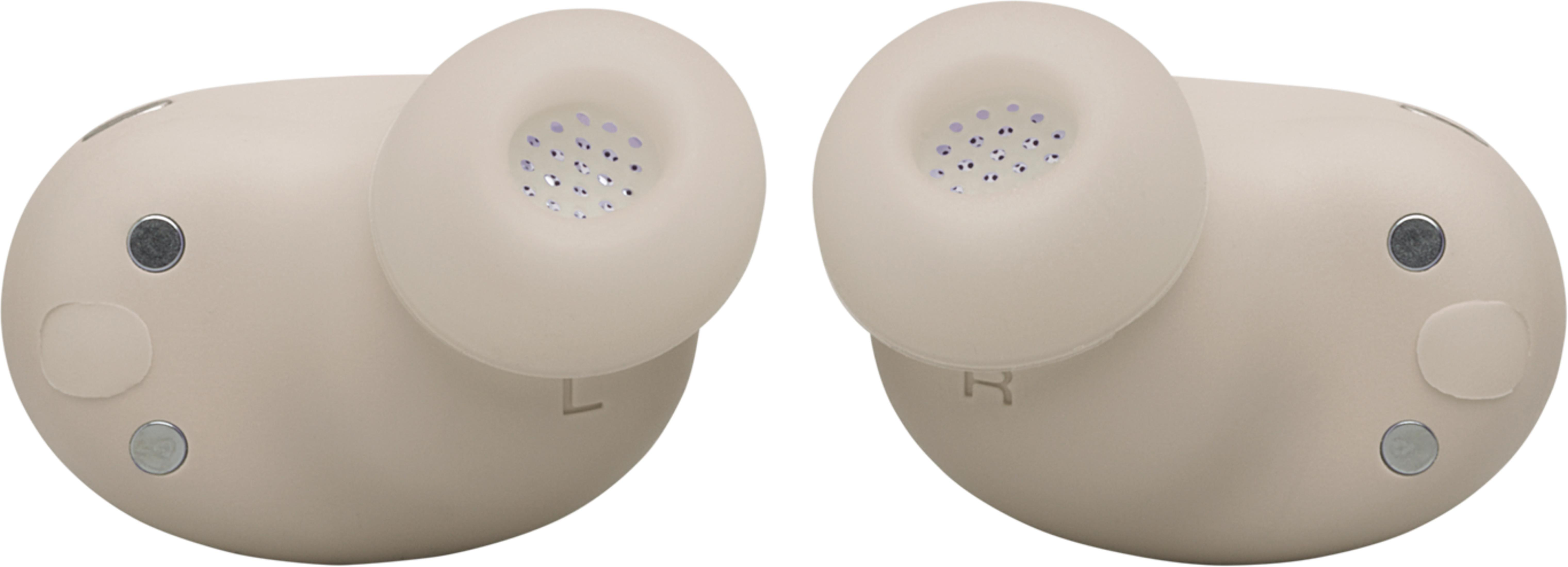 Due auricolari beige con contatti di ricarica e griglia.