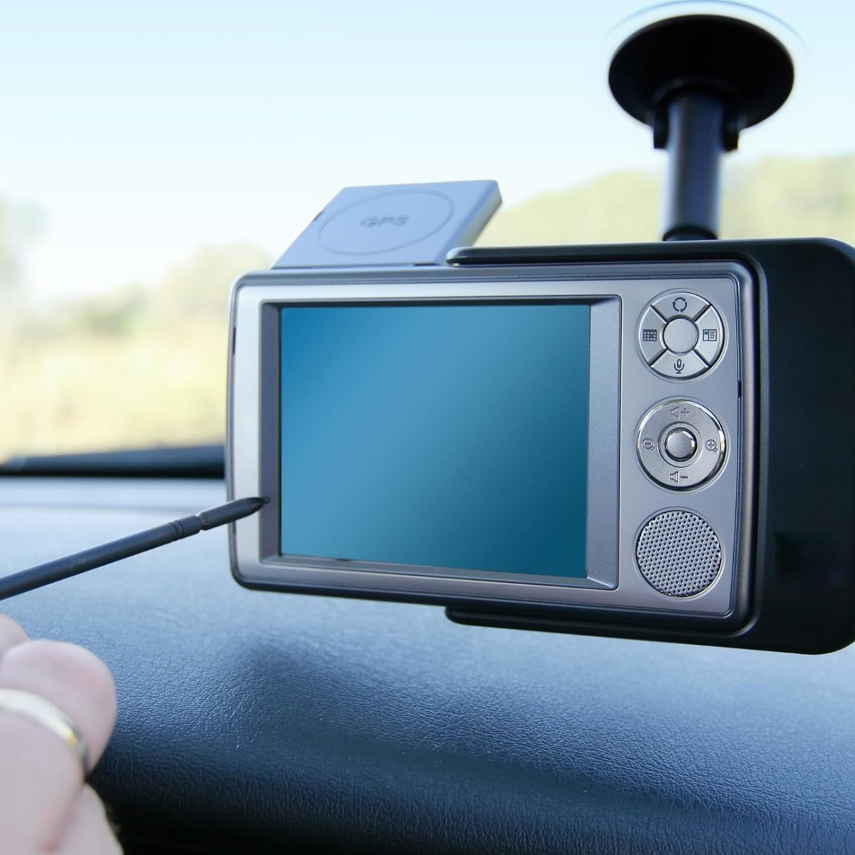Ein GPS-Gerät mit Stift, das an einer Windschutzscheibe befestigt ist. Draußen ist es hell.