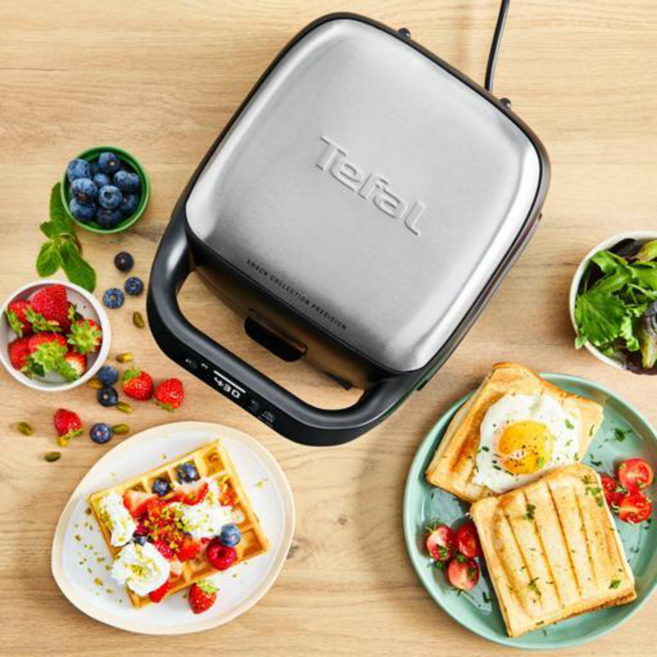 Tefal Sandwichmaker mit Waffel, Toast mit Ei und Salat auf Holzhintergrund.