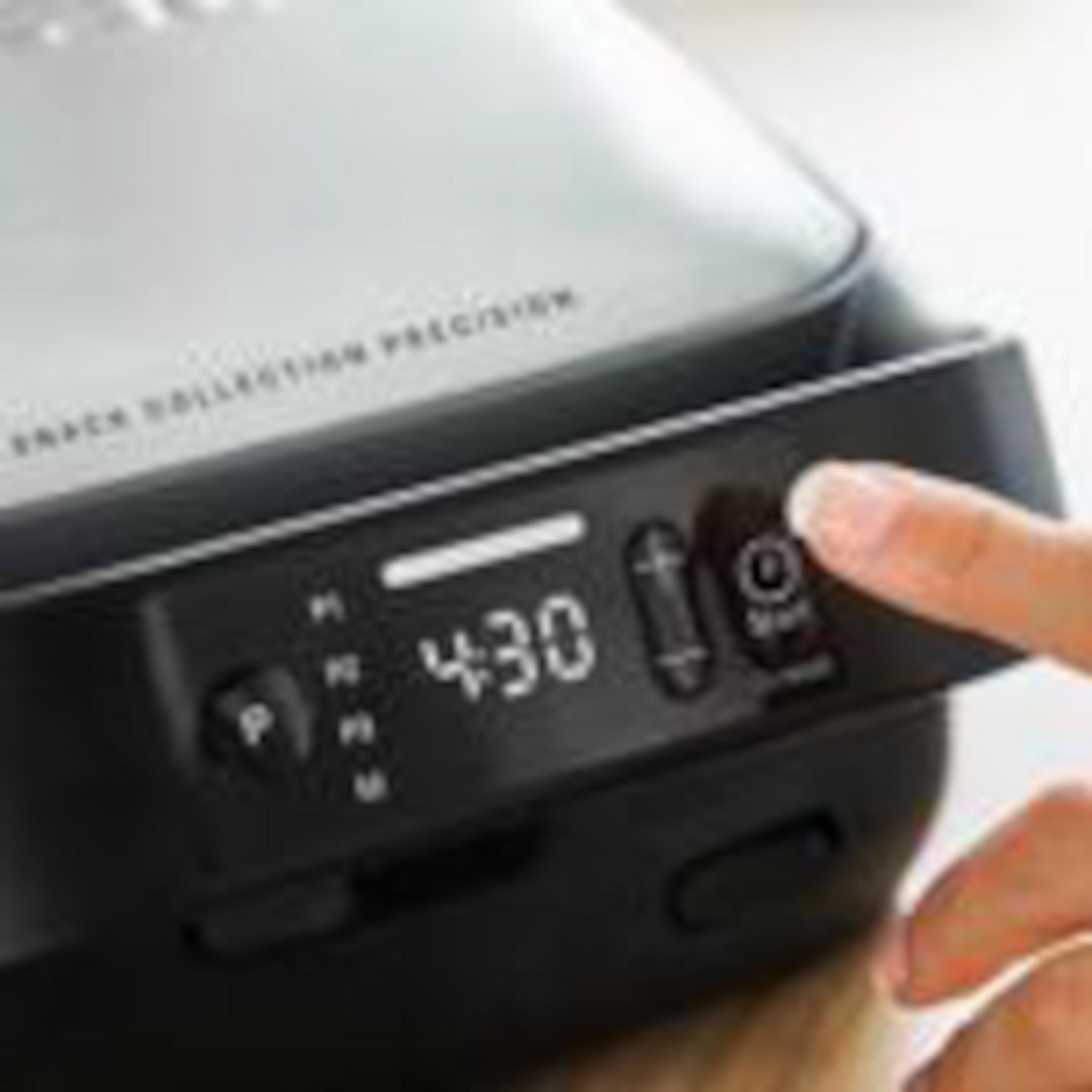 Eine Person bedient ein schwarzes Gerät mit digitaler Anzeige 4:30.