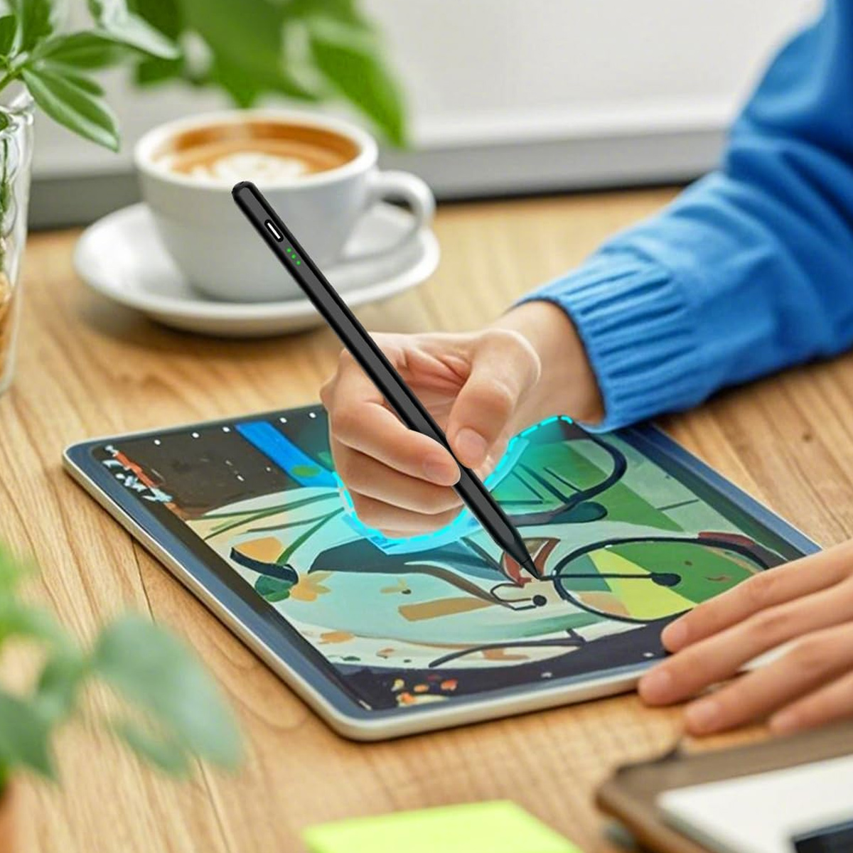Eine Hand mit einem Stift zeichnet auf einem Tablet, Kaffee im Hintergrund.