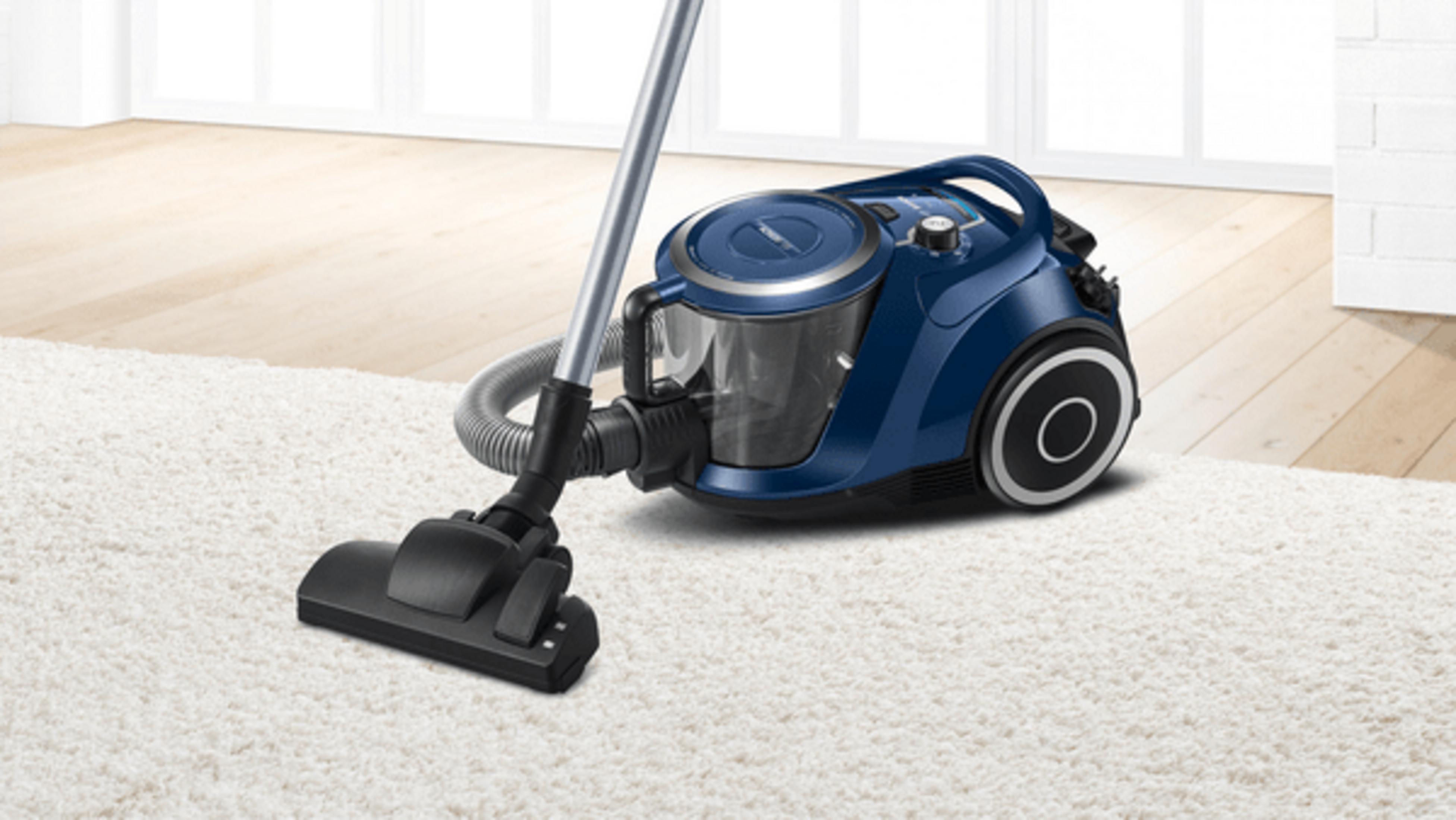 Un aspirapolvere blu con ugello nero su tappeto bianco.