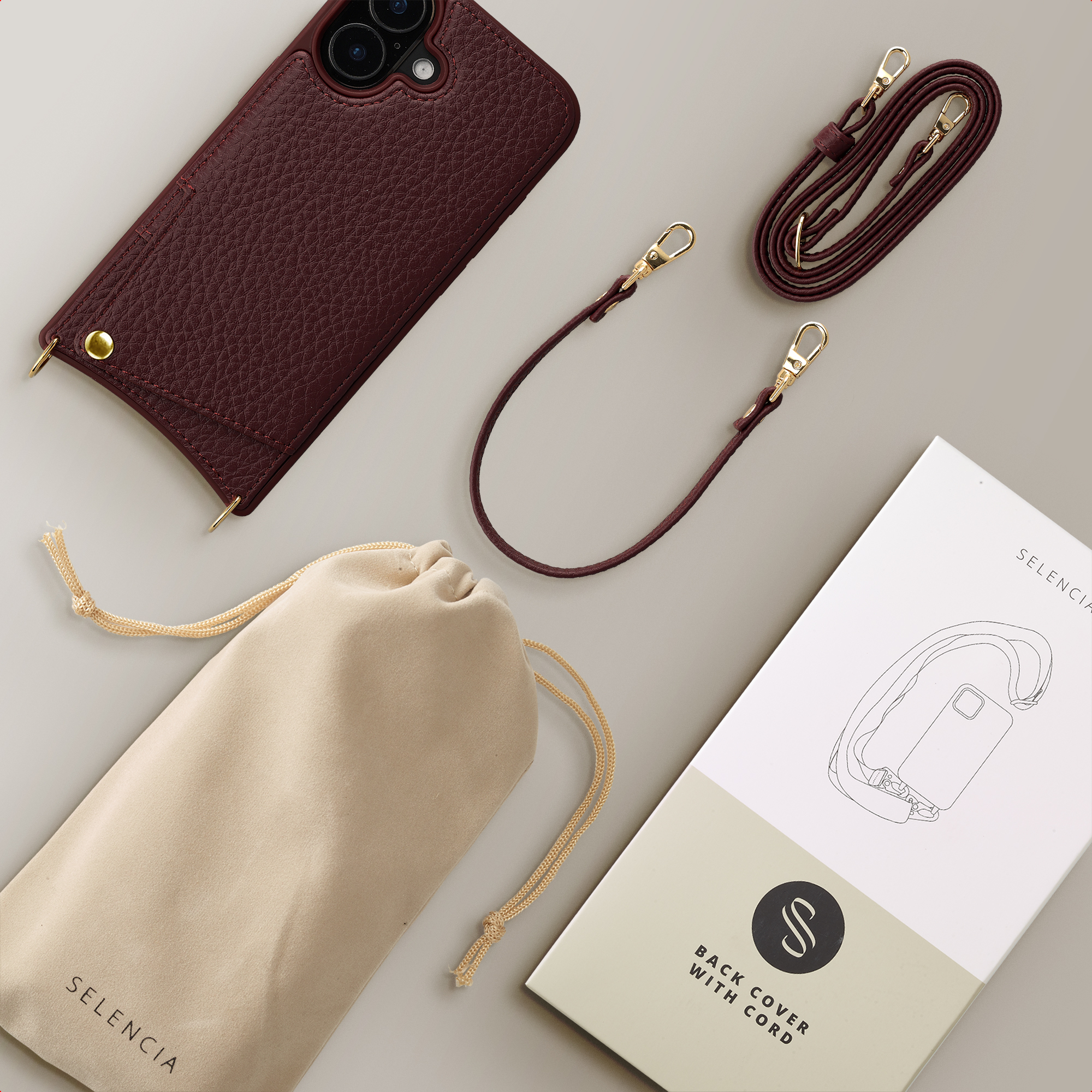 Burgundy leather iPhone case with cord, pouch, and packaging.