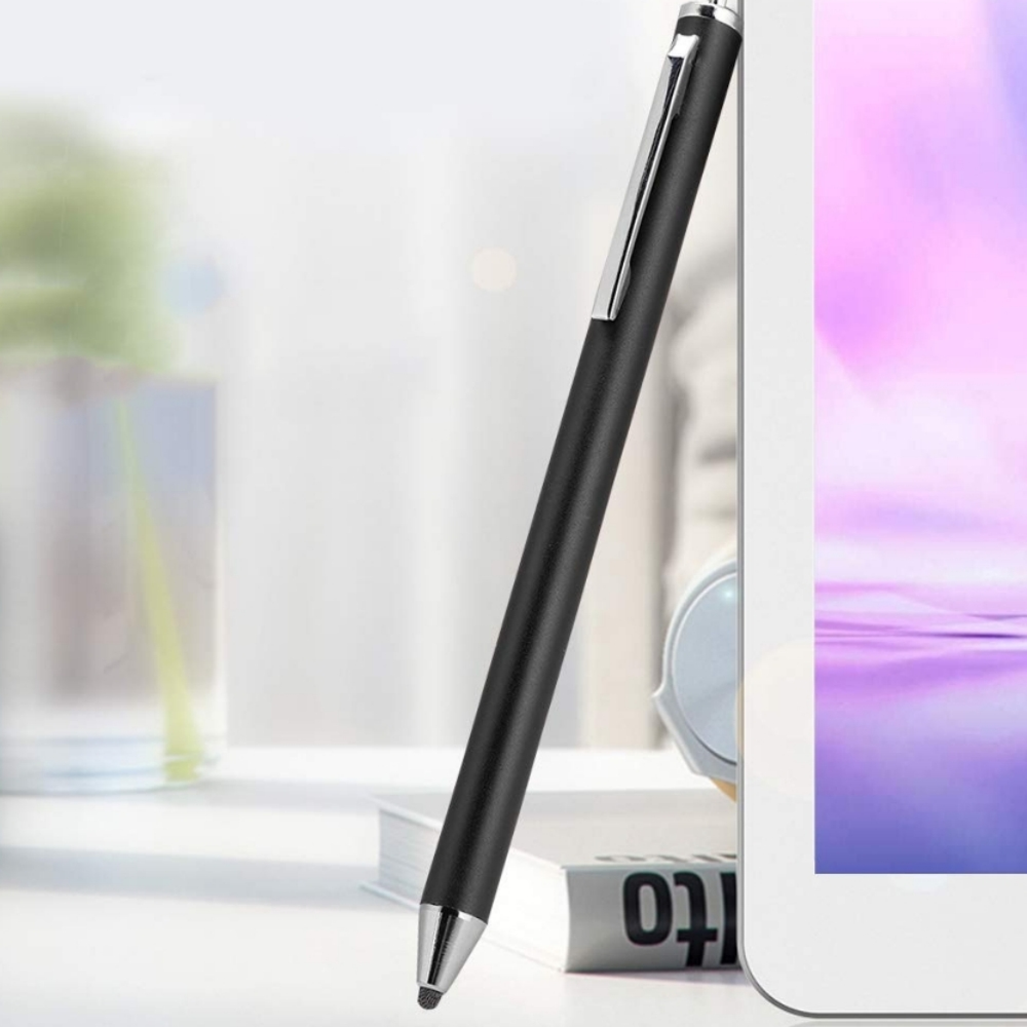 Ein schwarzer Stift mit silbernem Clip lehnt an einem Tablet.