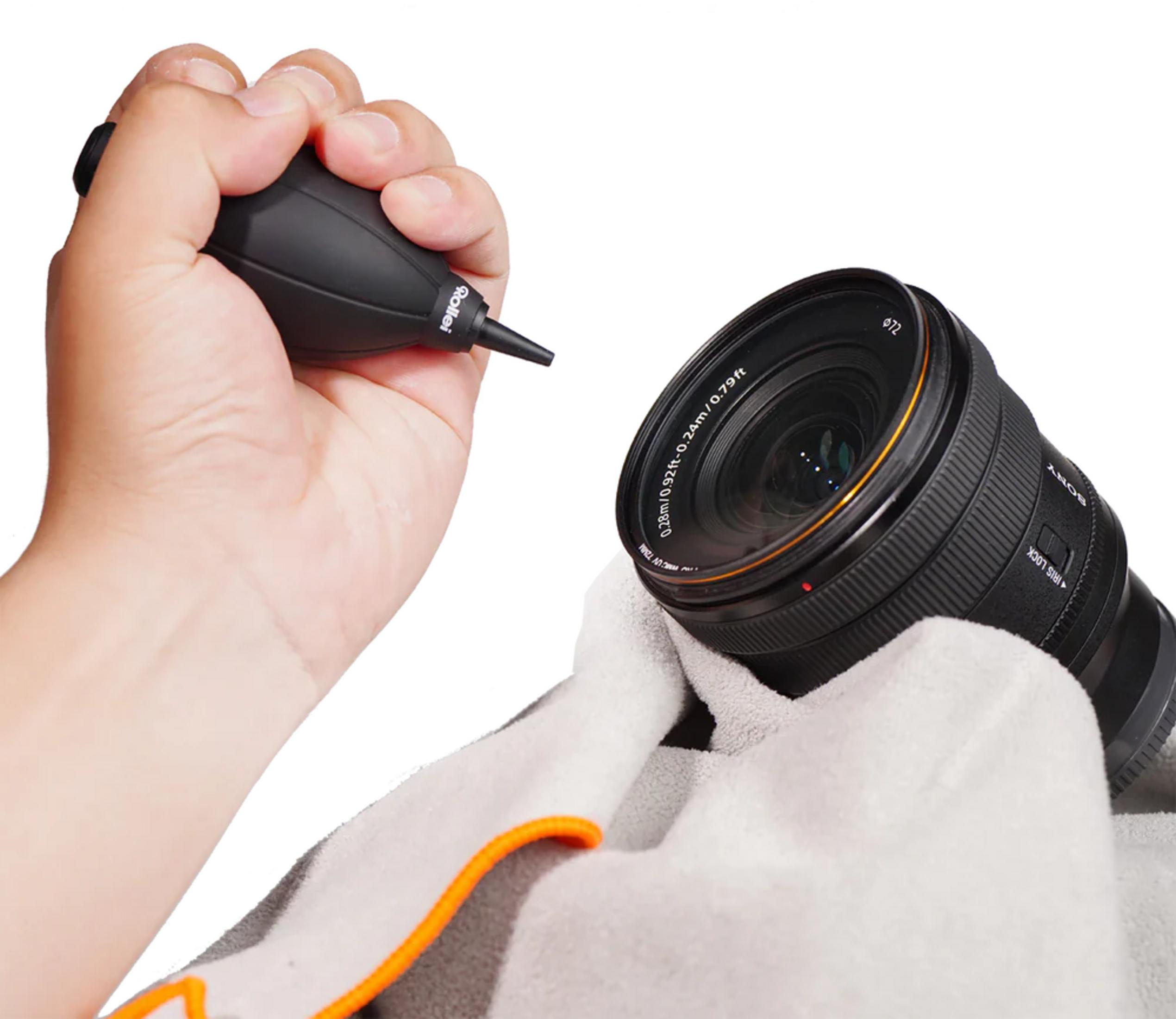 Eine Hand hält einen schwarzen Blasebalg, eine andere Hand mit Handschuh hält eine Sony-Kamera.