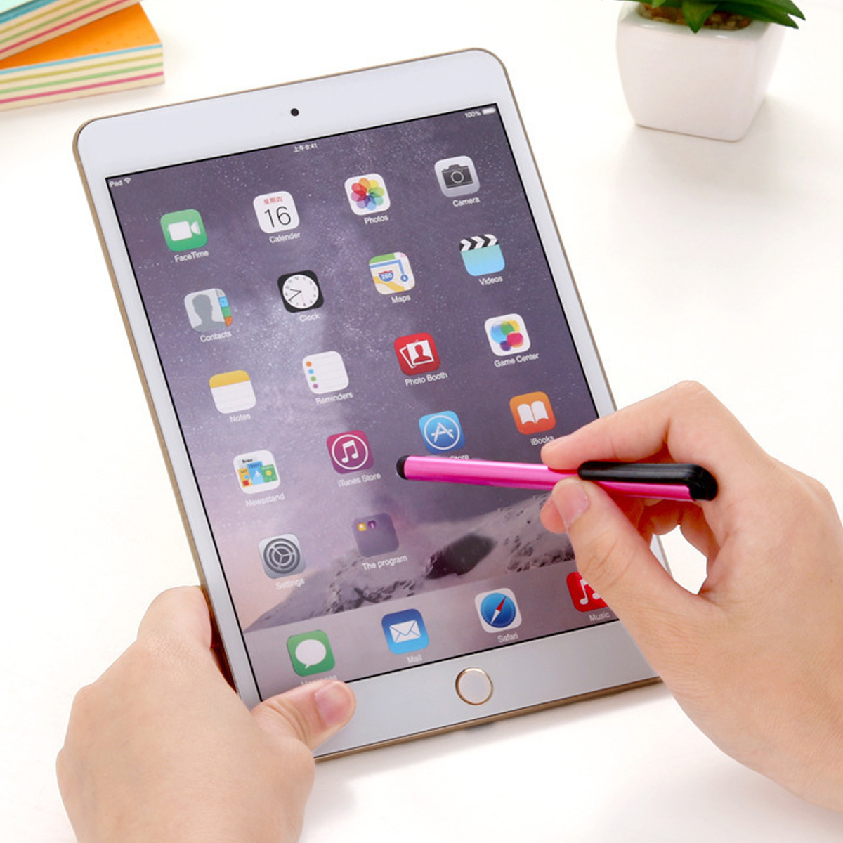 Eine Hand hält ein Tablet mit rosa Stift. Apps auf dem Bildschirm.