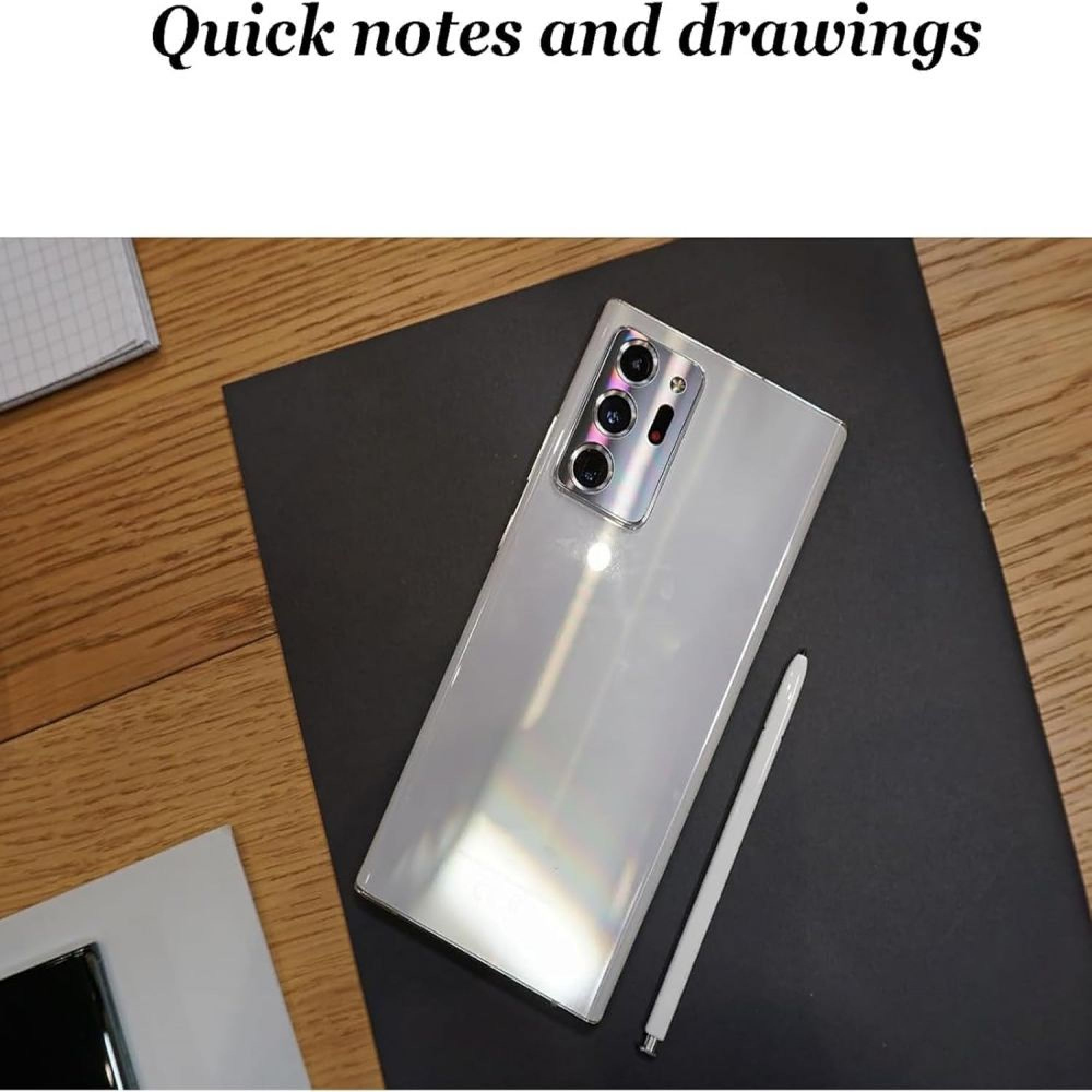 Ein weißes Smartphone mit Stift liegt neben einem Notizbuch auf schwarzer Unterlage.