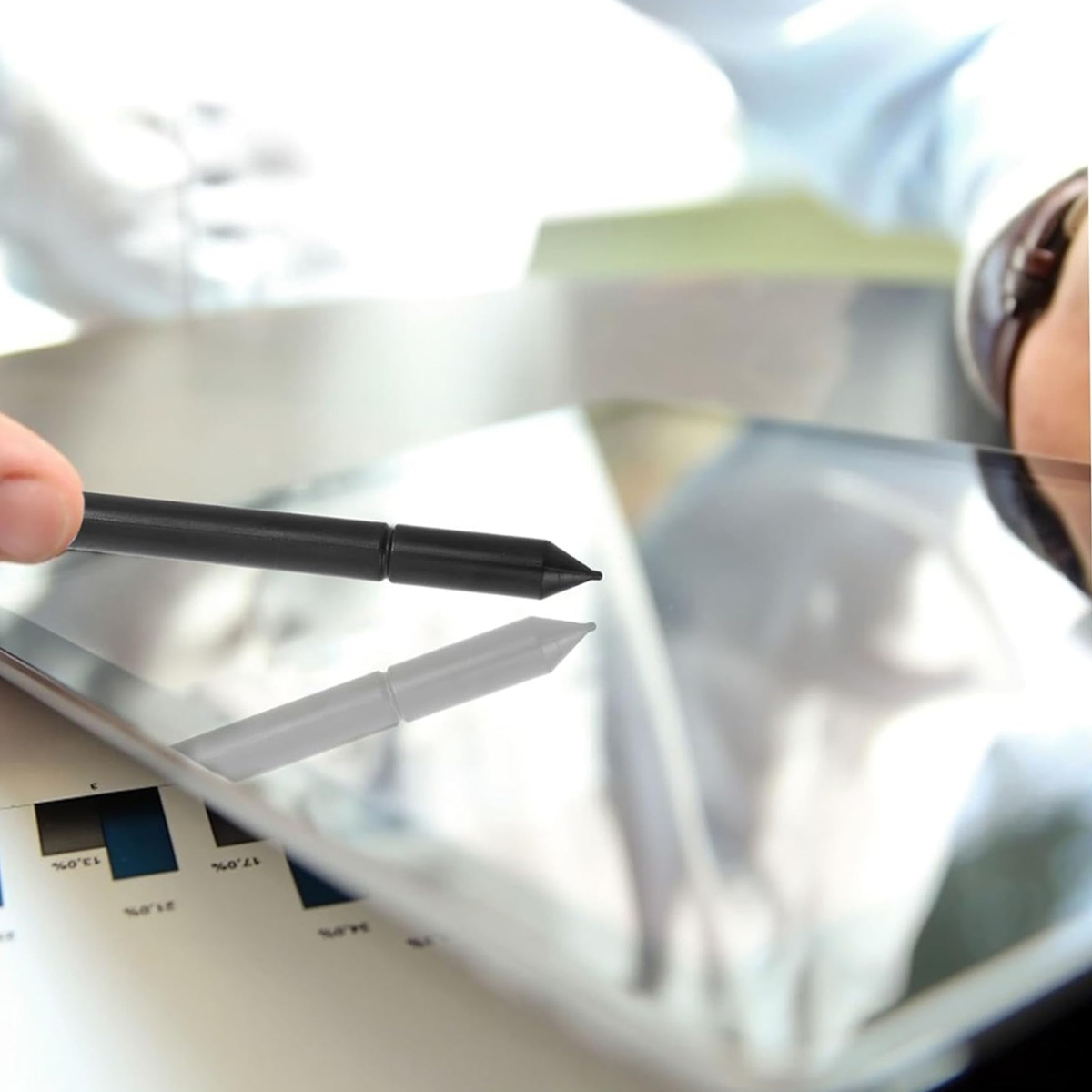 Ein schwarzer Stift wird über ein Tablet gehalten, das auf einem Diagramm liegt.