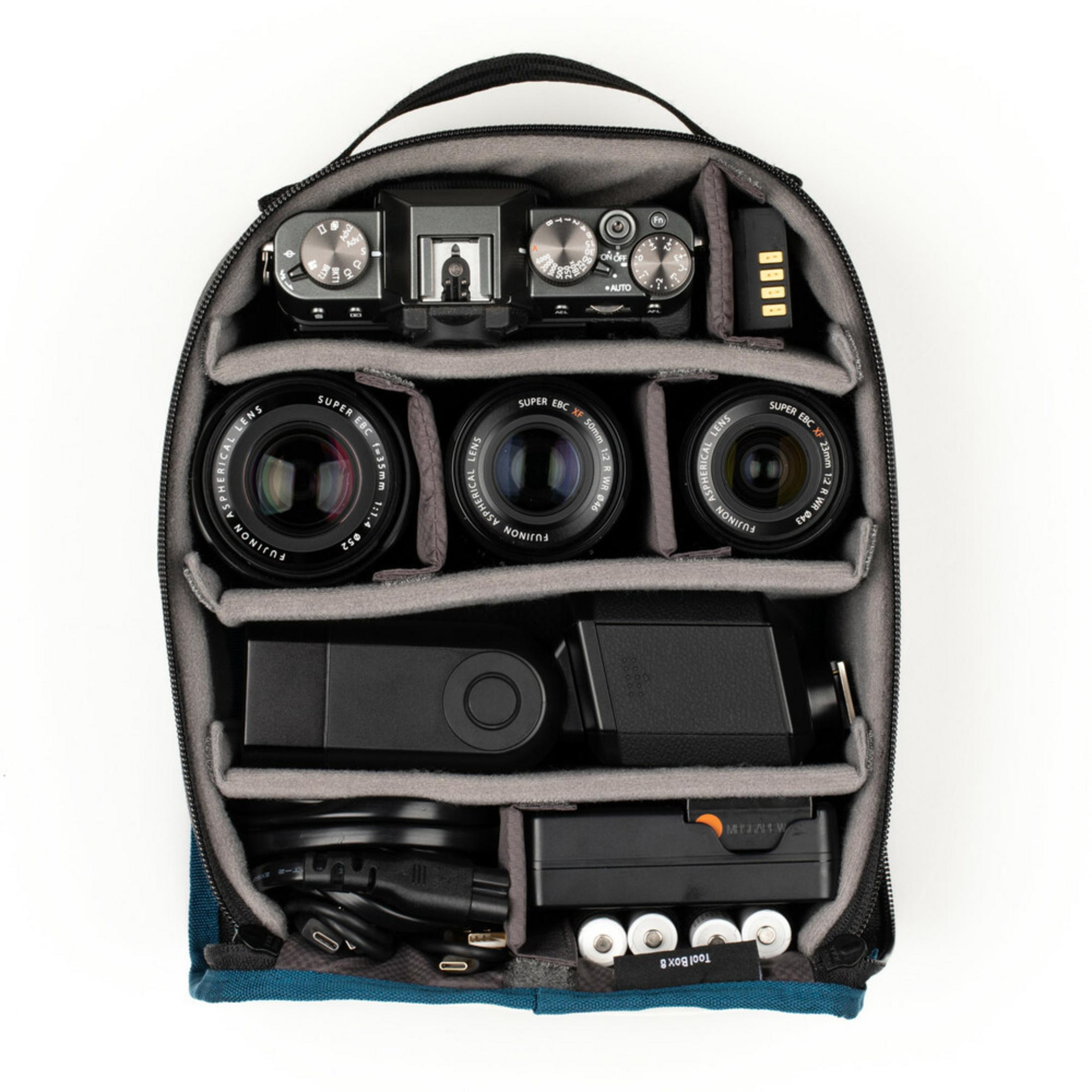Camera bag with camera, three lenses, battery, flash, and cables inside.