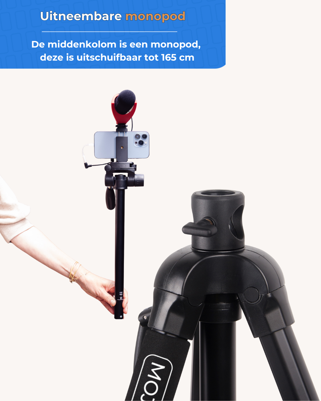 A hand holds an extendable monopod with phone and mic above a tripod.