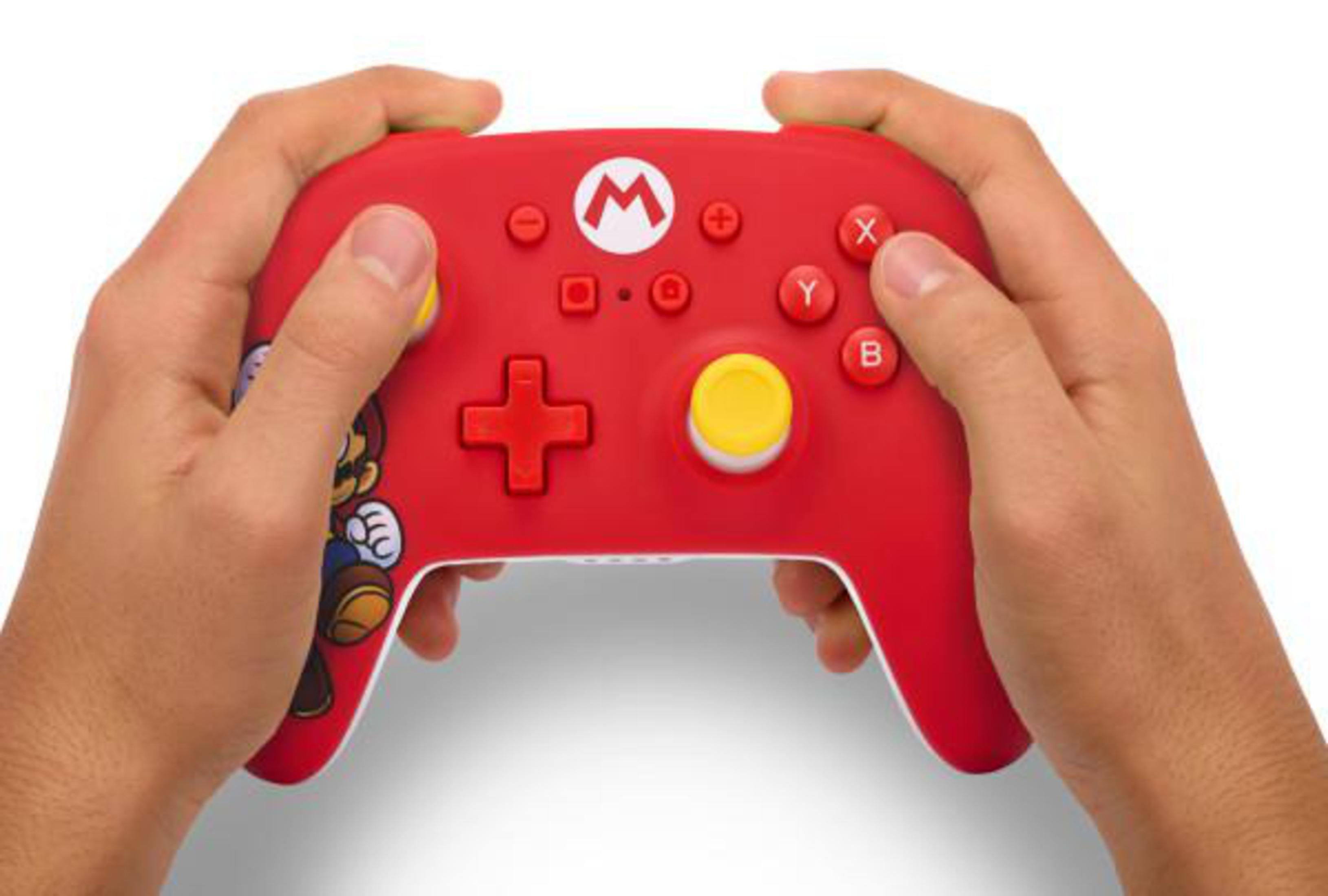 Mando Pro de Nintendo Switch rojo con diseño de Mario, sostenido por manos.