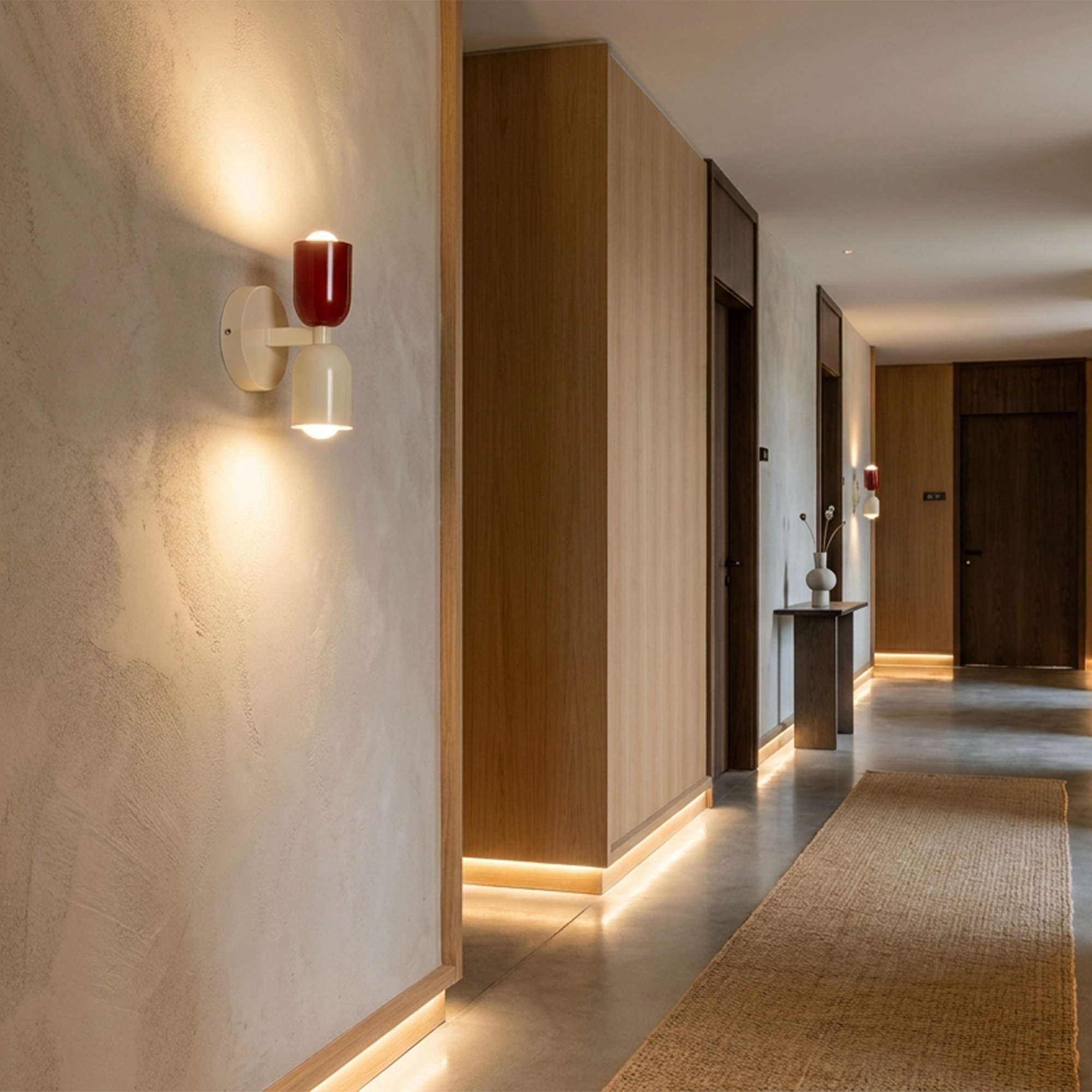 Un pasillo luminoso con detalles de madera y un aplique de pared. Una alfombra en el suelo.