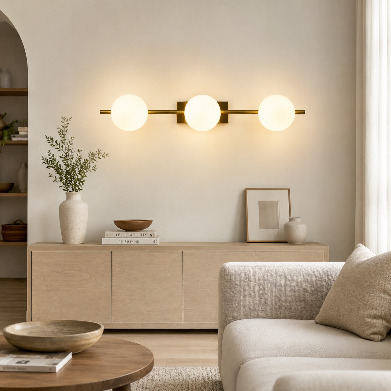 Una sala de estar moderna con una lámpara dorada de tres esferas sobre un mueble de madera.