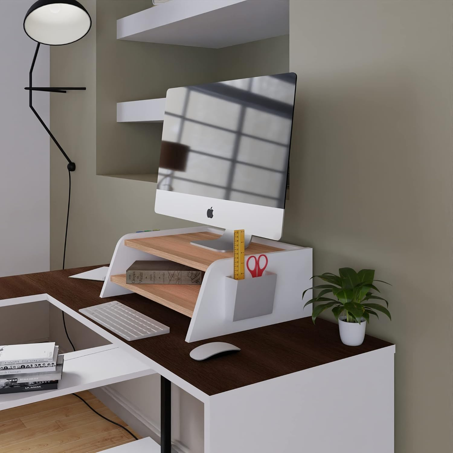 Un escritorio moderno con computadora, teclado, ratón, libros, planta y lámpara.