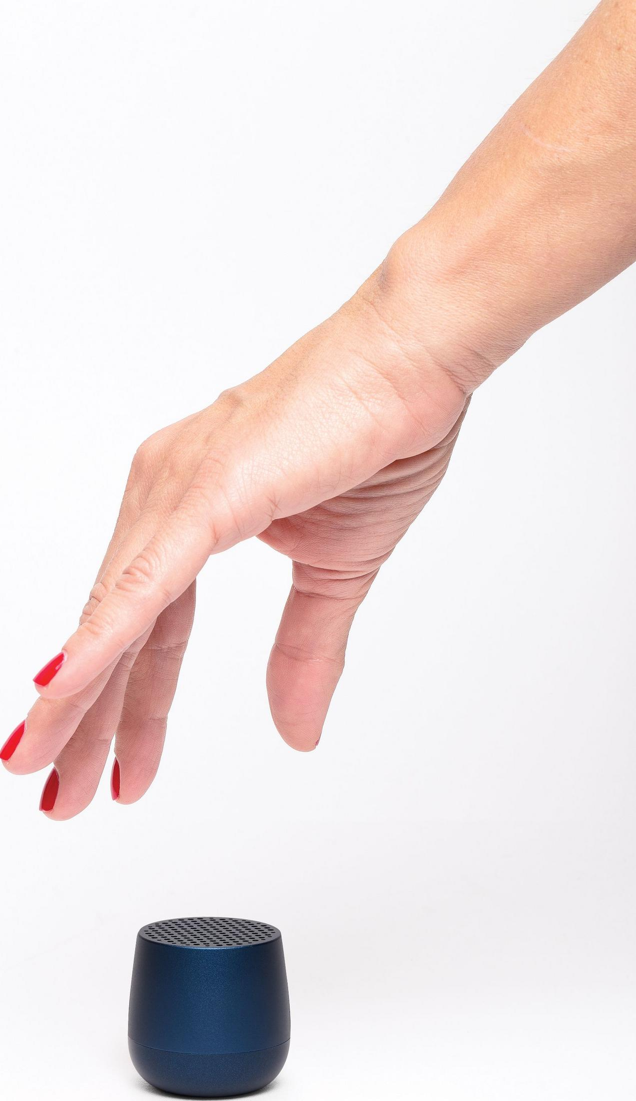 Eine Hand mit roten Nägeln nähert sich einem kleinen blauen Lautsprecher.