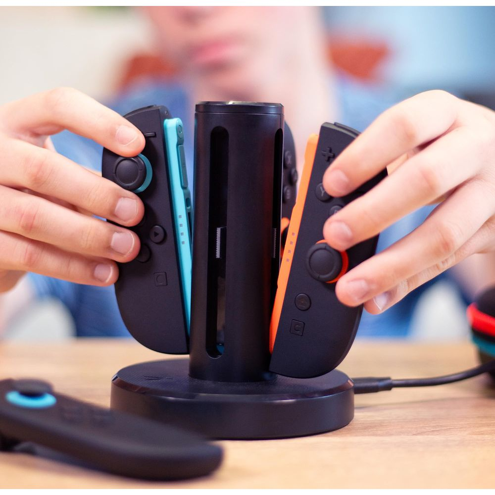 Personen laden Joy-Cons in eine schwarze Ladestation.