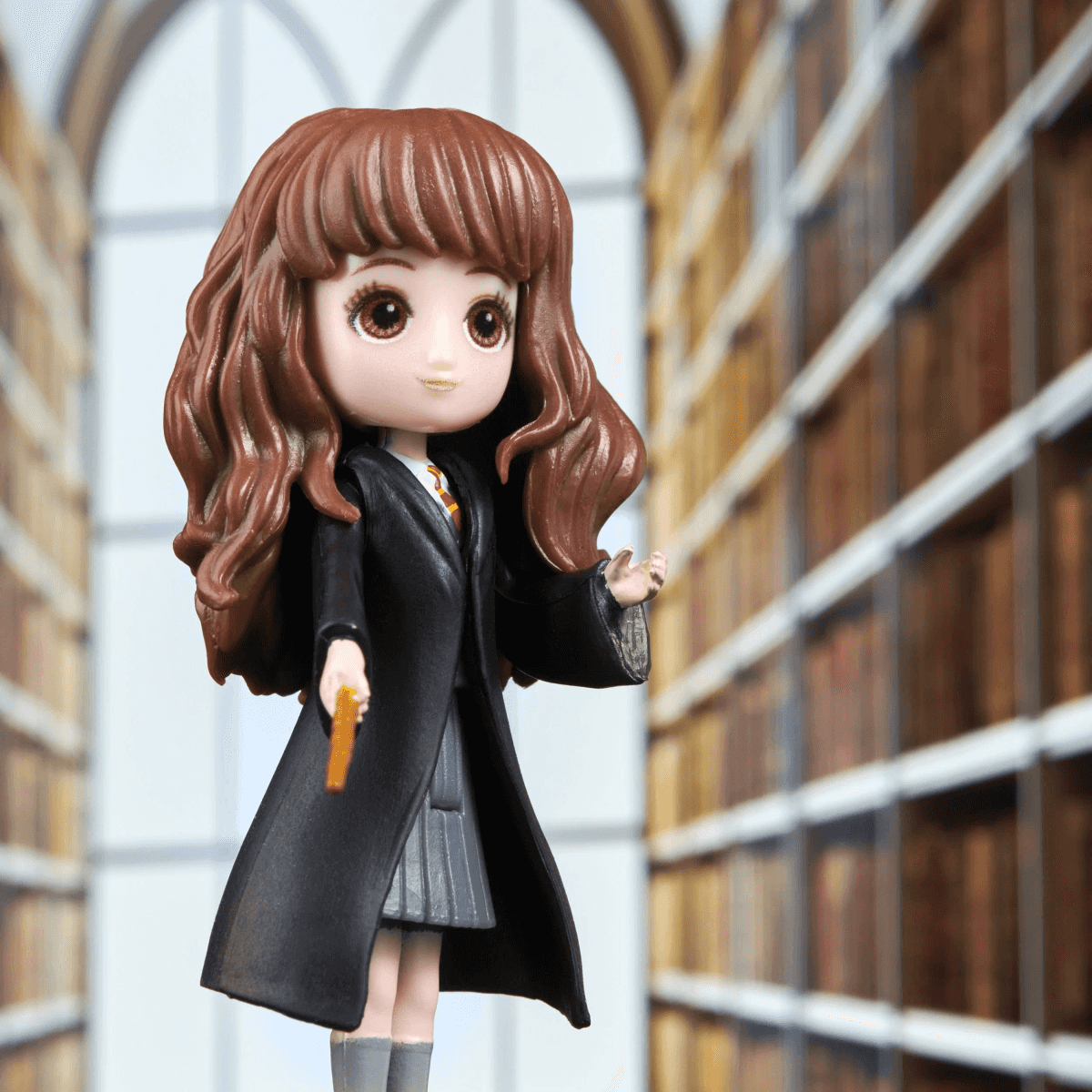 Eine Puppe im Stil von Hermine Granger steht vor einem Bücherregal.