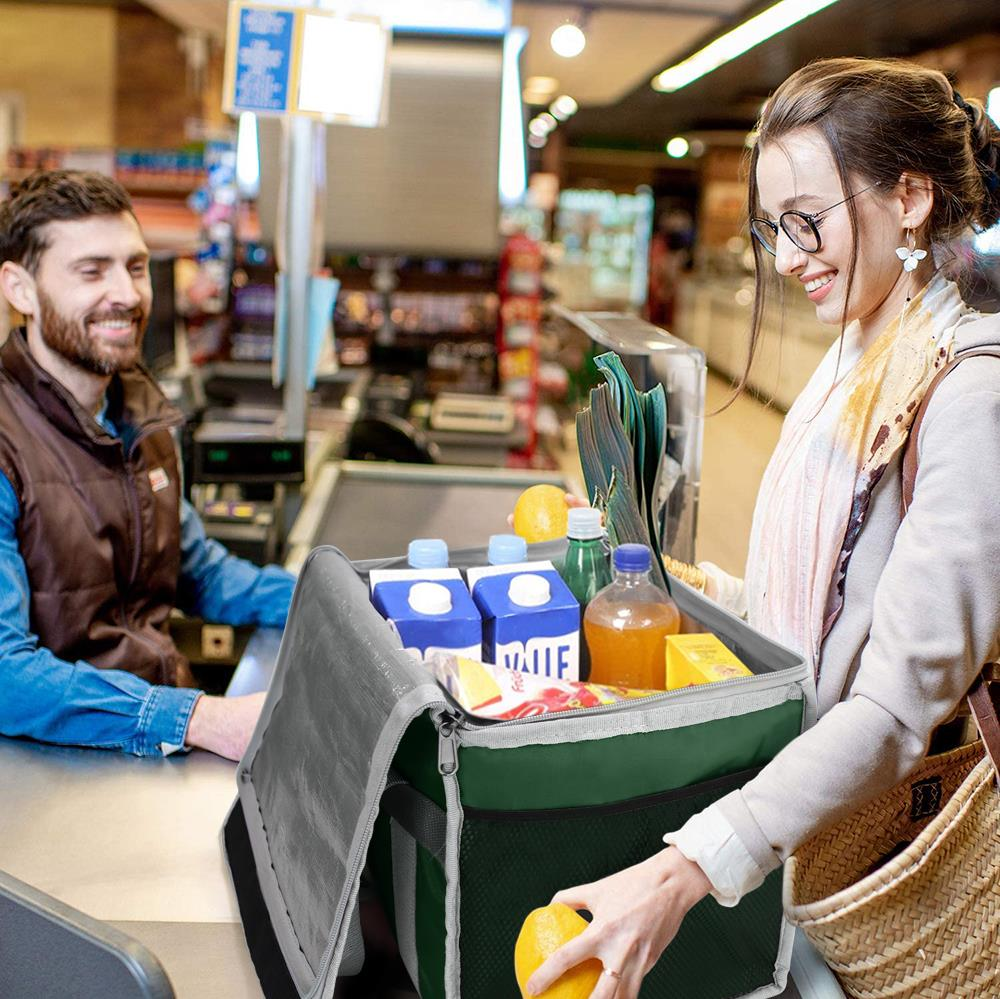 Bir kadın kasiyerin yanında bir market çantasına portakal koyuyor.