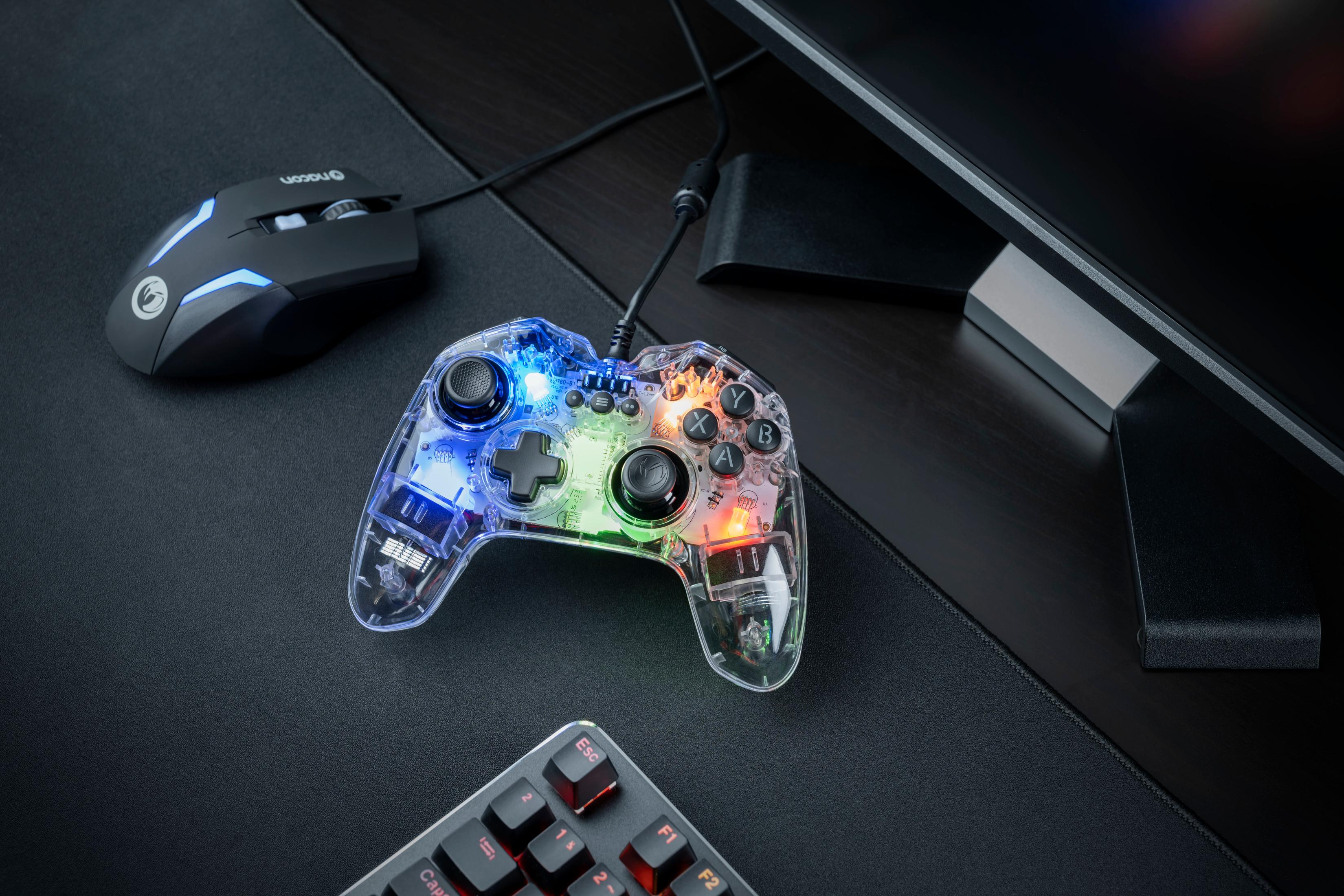 Ein durchsichtiger Controller leuchtet bunt neben einer schwarzen Maus auf einem schwarzen Mauspad.