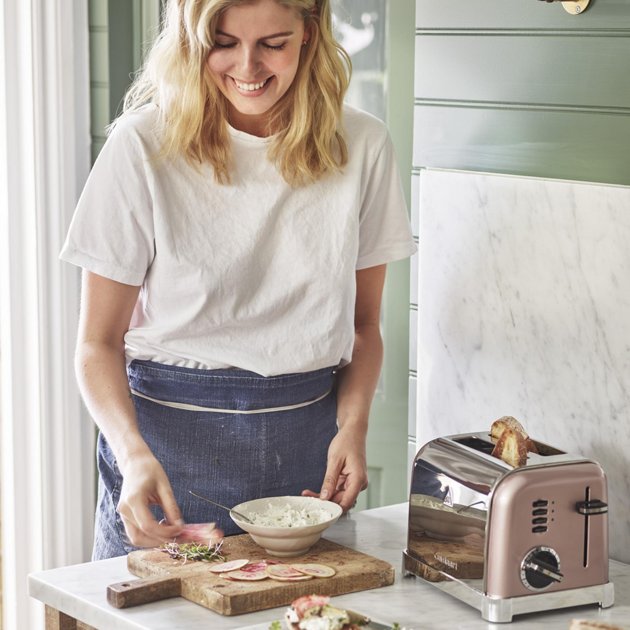 Donna prepara cibo, tostapane con pane sullo sfondo.