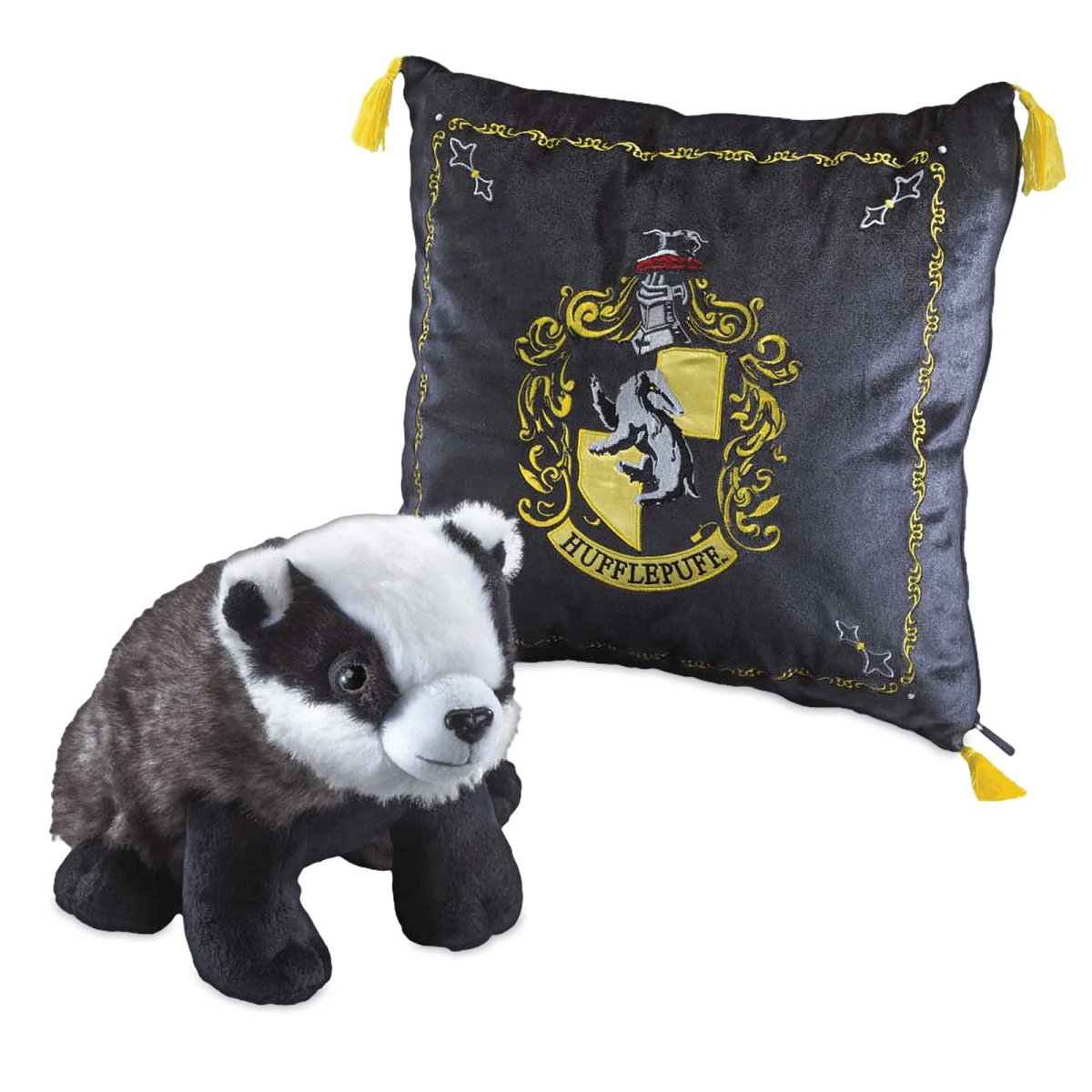 Un tejón de peluche junto a un cojín negro de Hufflepuff con ribete y borlas amarillas.