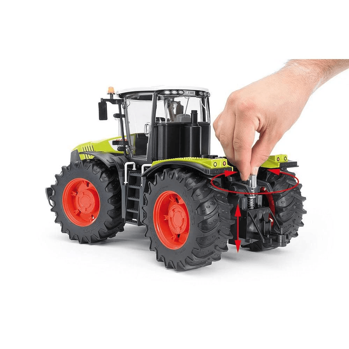 Una mano acciona el enganche de un tractor de juguete verde con llantas rojas.