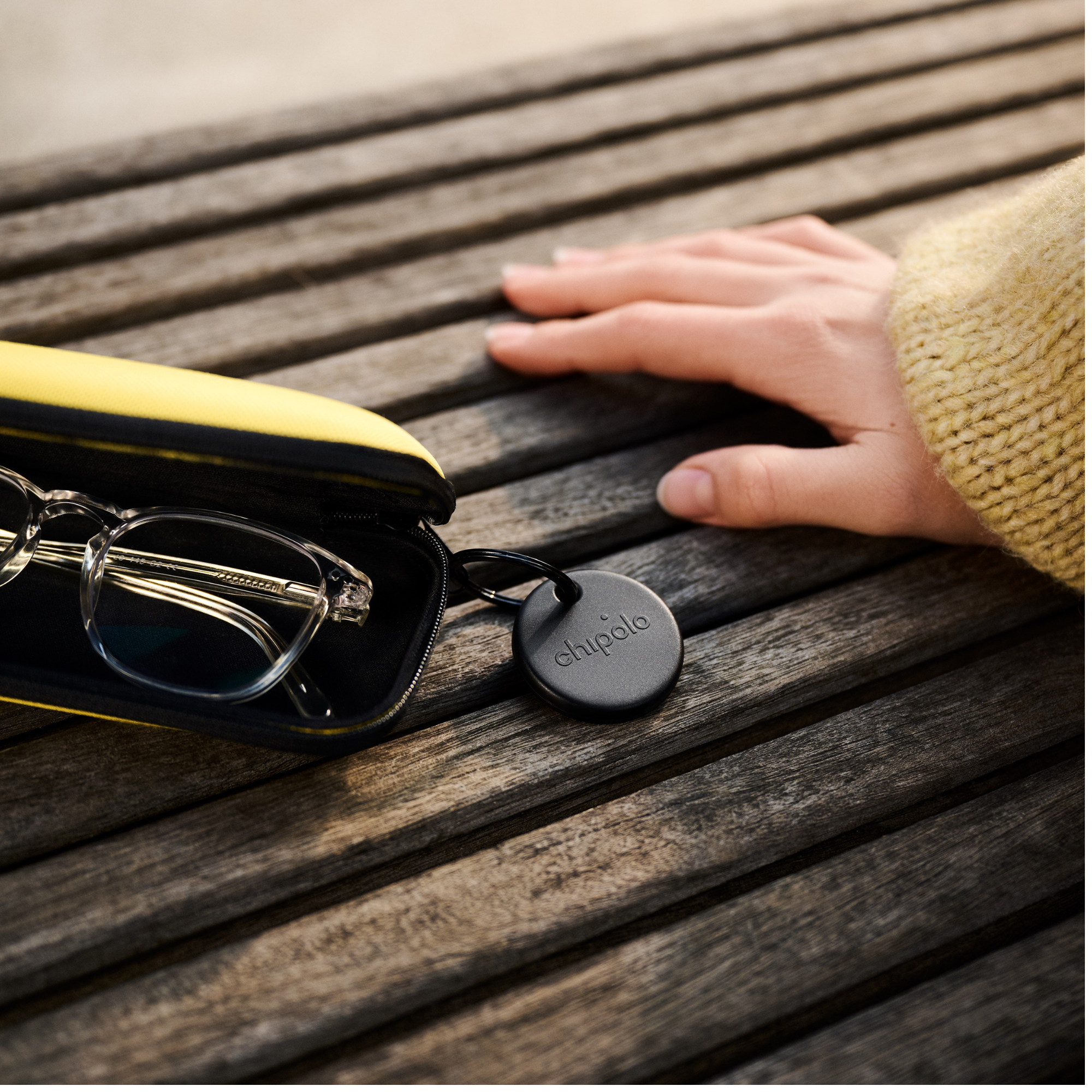 Clear glasses in yellow case on wood table next to a round tracker.