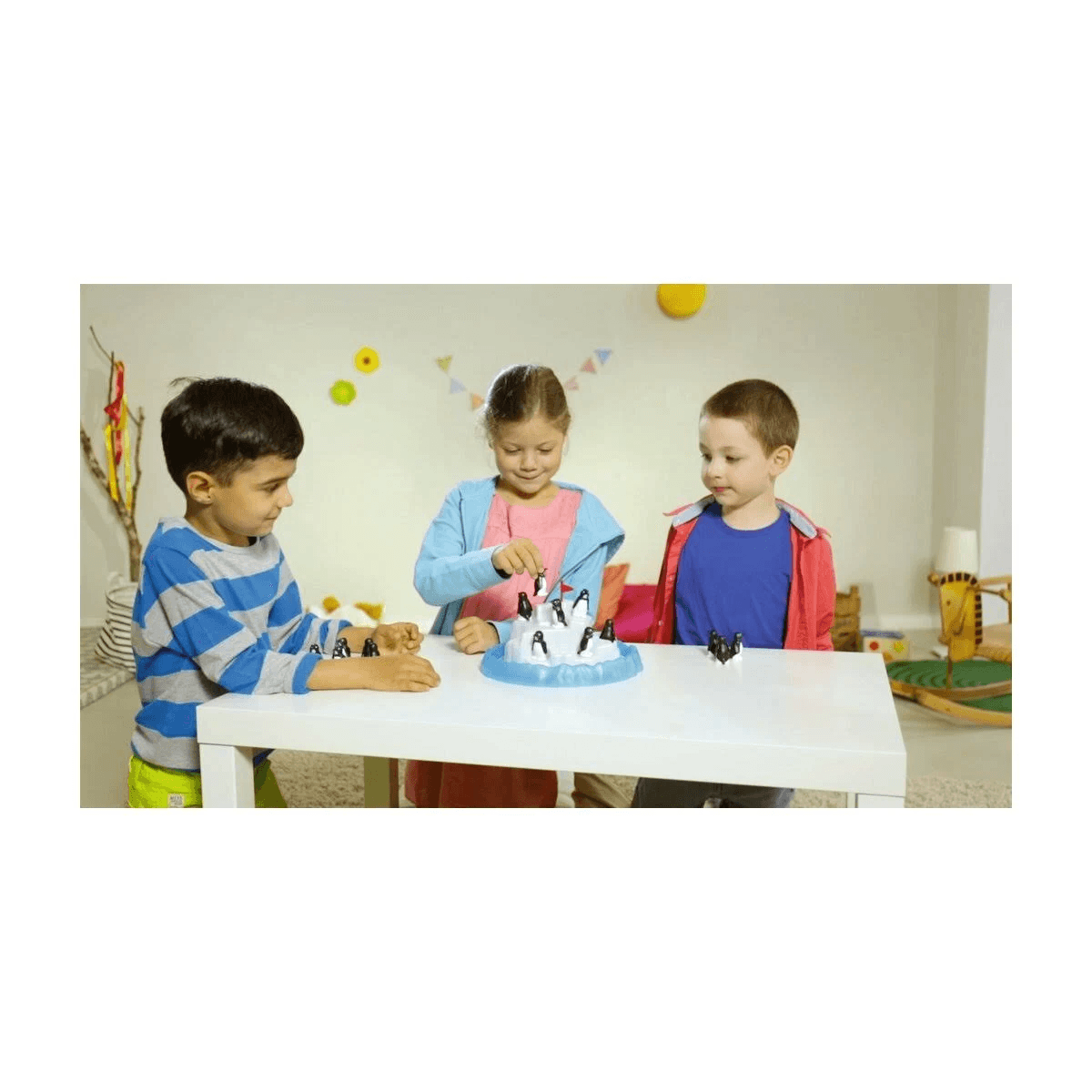 Drei Kinder spielen ein Pinguinspiel auf einem Eisberg auf einem Tisch.