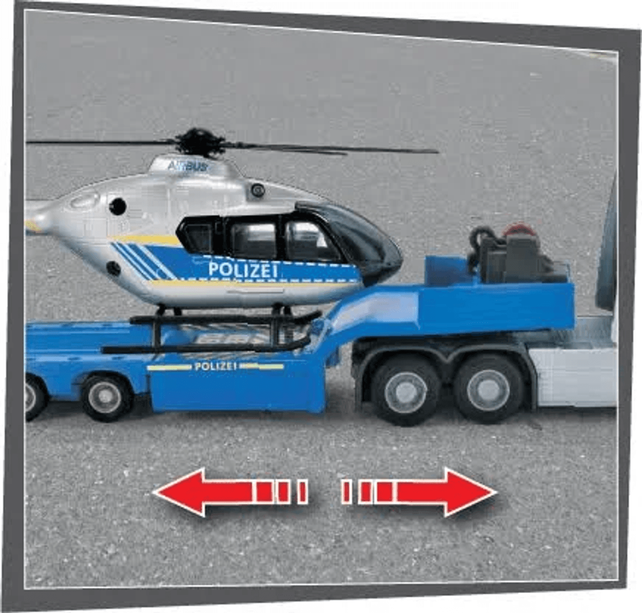 Ein Polizeihubschrauber auf einem blauen Tiefladeranhänger, der von einem LKW gezogen wird.